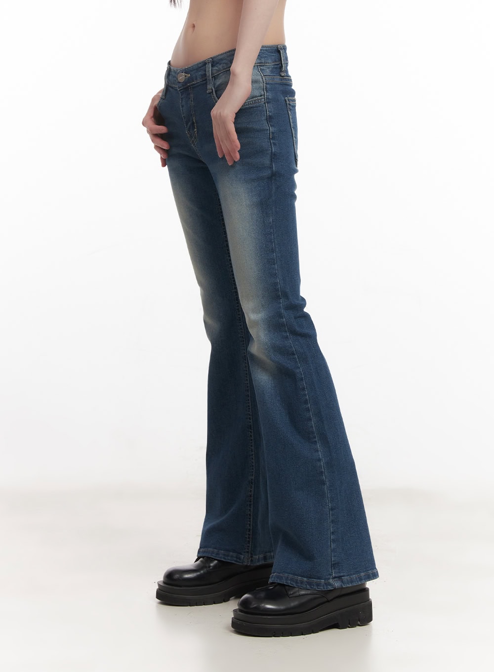 Rebecca Low-Waist Flared Jeans CM519 in dark blue, close-up side view on model, hand in pocket, showcasing low-rise waistband, whisker fading, and flared hem detail.