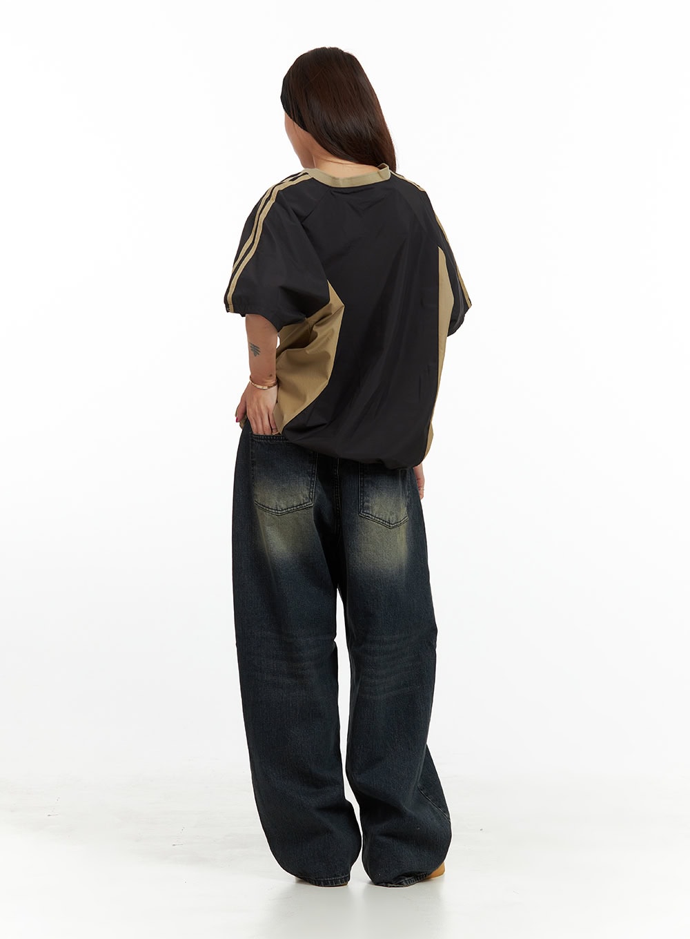 Solid Low Rise Baggy Jeans CU417 in dark blue, full-body back shot on model, low-rise baggy denim with yellow-toned wash and oversized leg pooling at hem, paired with black jersey top.