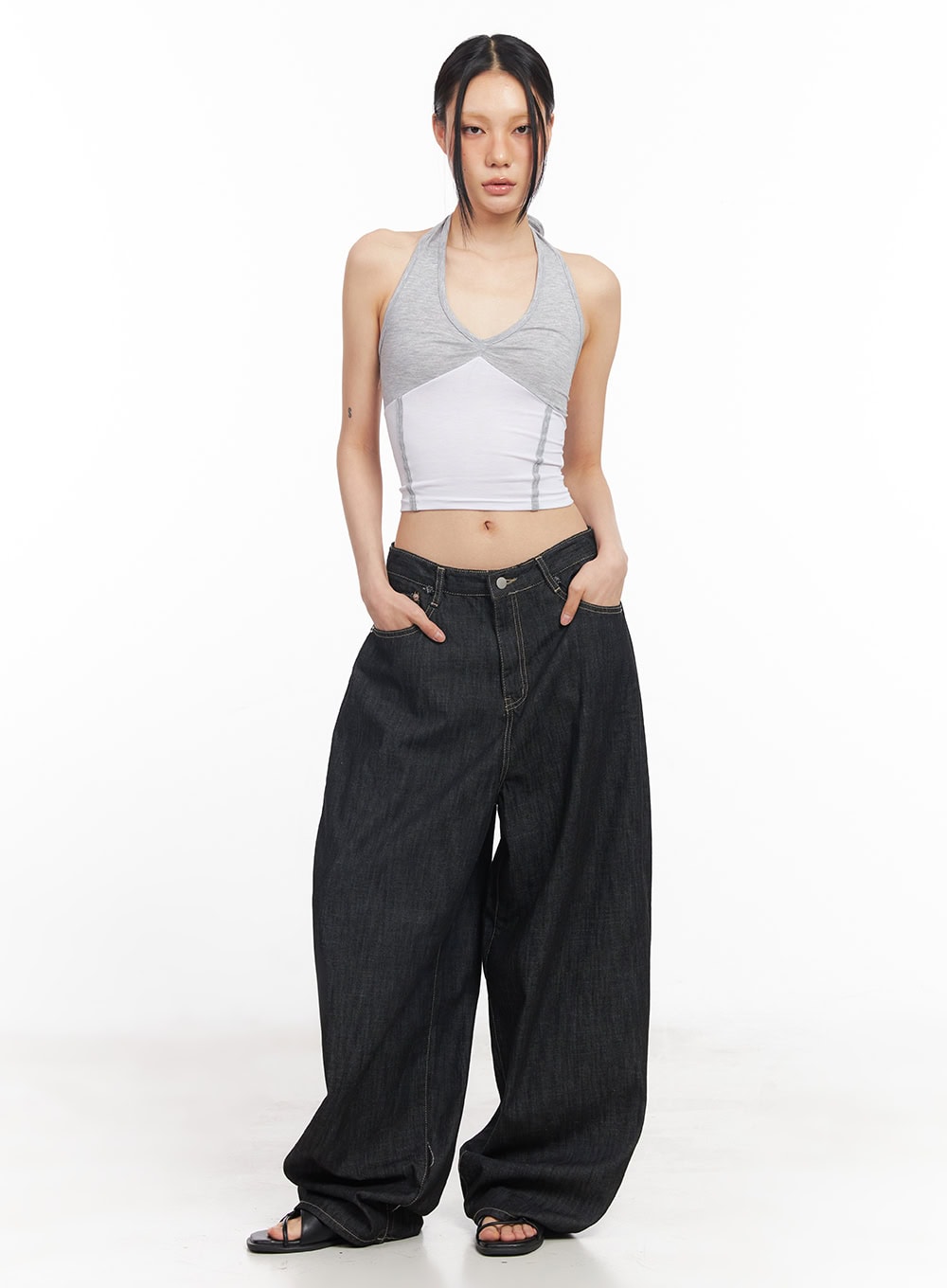 Elvie Baggy Jeans CY528 in black, front full-body shot on model, low-rise wide-fit cotton denim with contrast stitching, styled with a layered crop halter top.