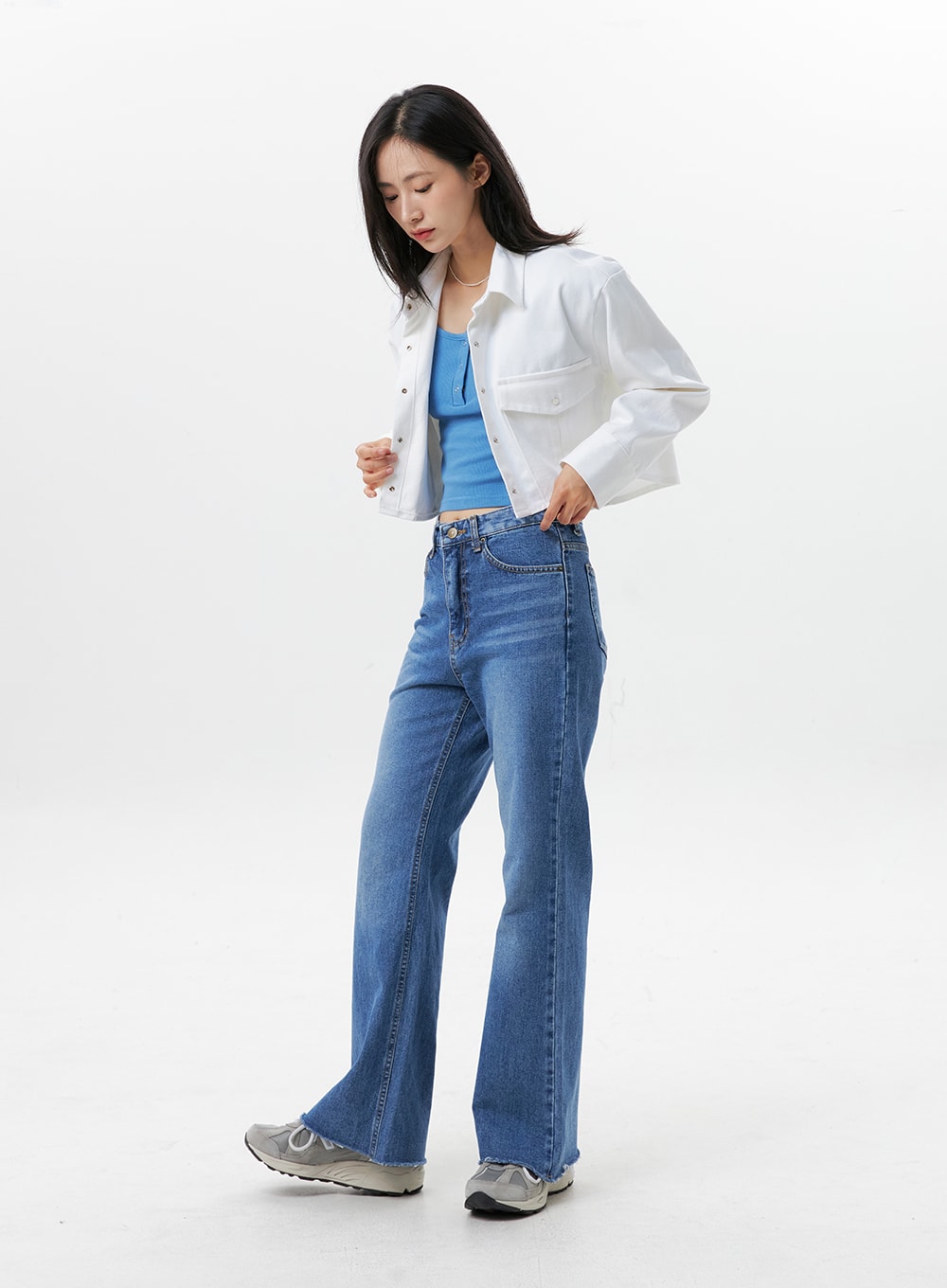 Straight-Leg Jeans OG318 in medium blue, side-angle full-length on model, high-rise straight denim showing leg silhouette and raw frayed hem, layered with white cropped jacket and blue top.