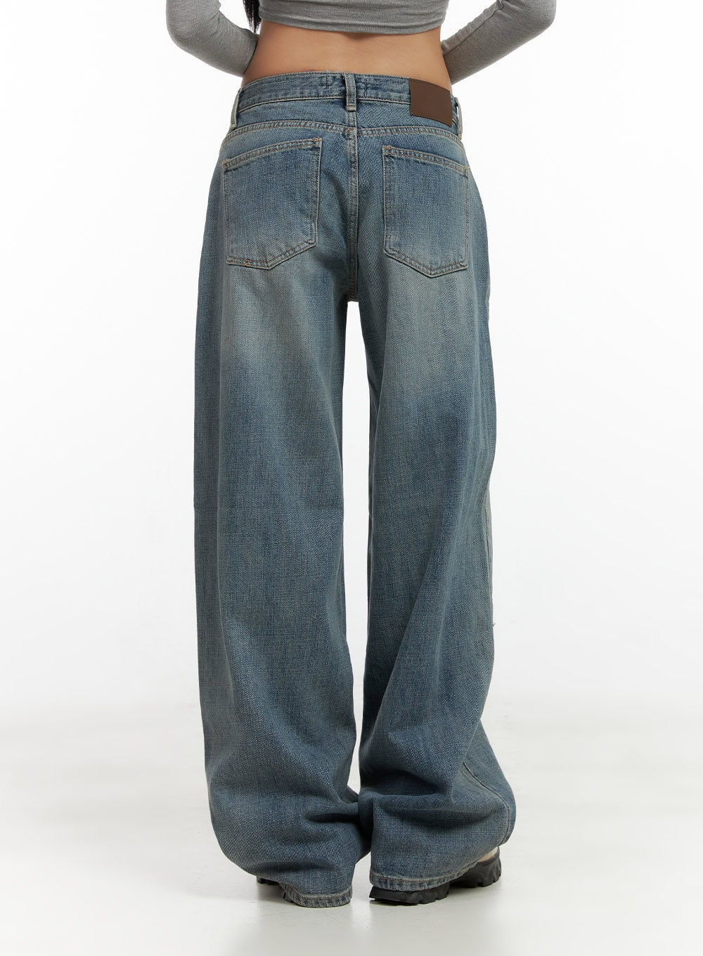Nadia Washed Low-Waist Baggy Jeans CO424 in blue, back close-up on model, showing two back patch pockets, brown leather logo patch on waistband, wide-leg washed denim silhouette.
