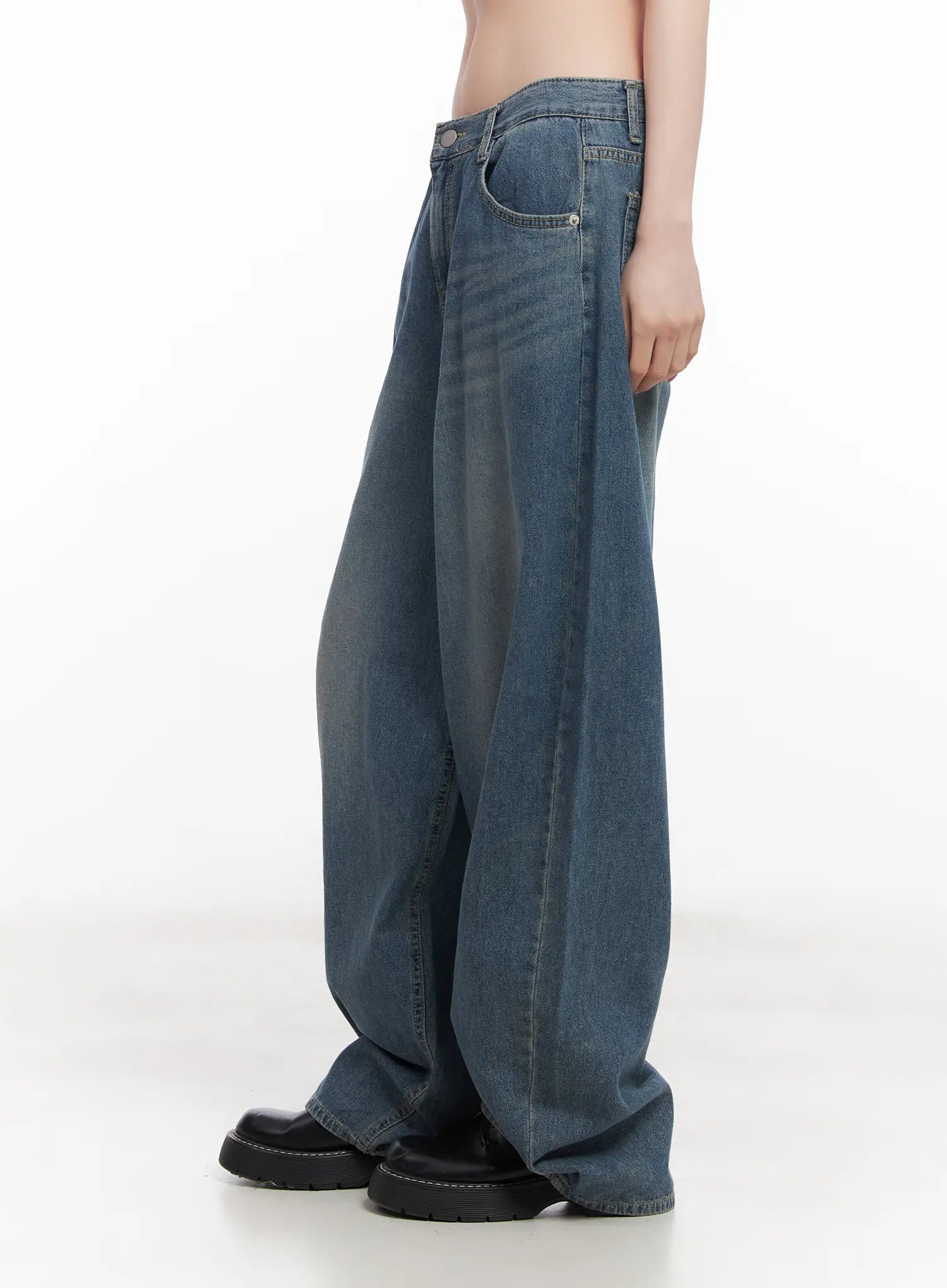 Chaewon Washed Wide-Leg Jeans CU511 in blue, close-up side view on model, low-rise waistband and exaggerated wide-leg sweep visible, washed denim with subtle fading.