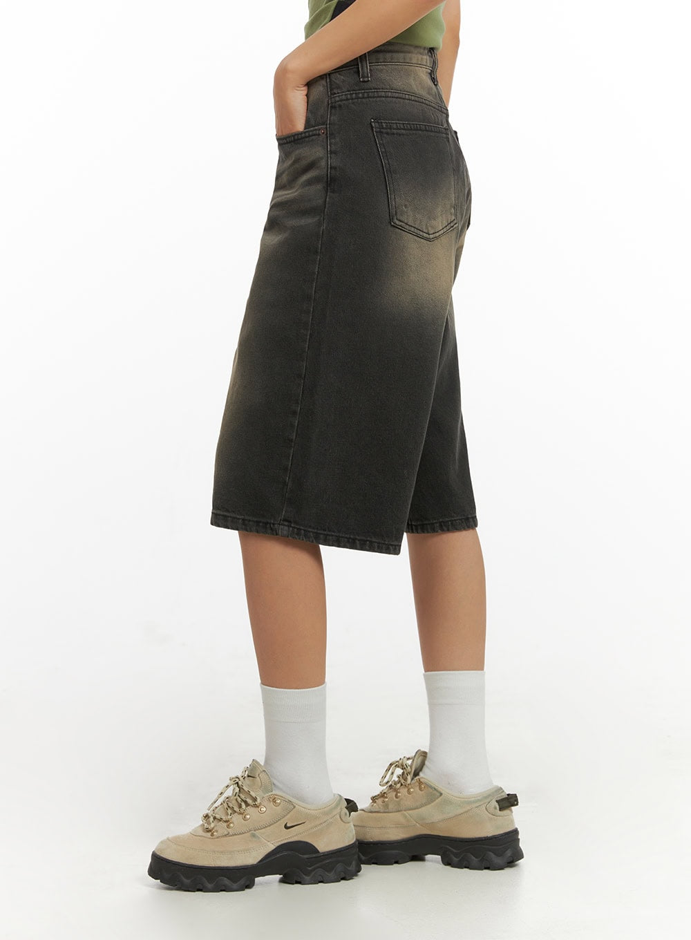 Color Washed Jorts IY422 in black washed denim, side view on model, wide-leg silhouette with back pocket visible, knee-length hem, paired with green tank and chunky sneakers.