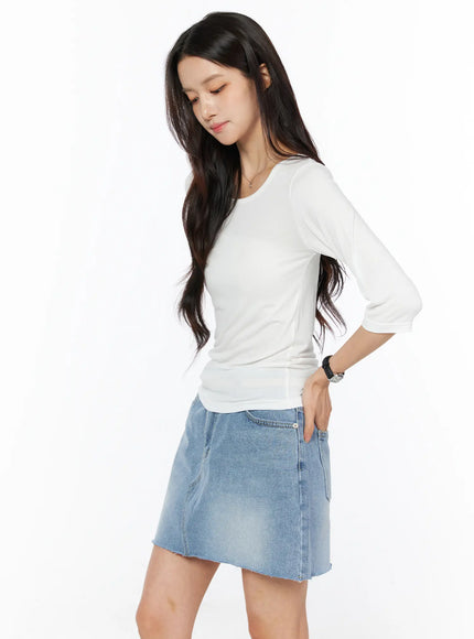 Sheer Three-Quarter Sleeve Top CU522 in white, side view on model looking down, slim sheer fit highlighting side seam and three-quarter sleeve length, with denim mini skirt.