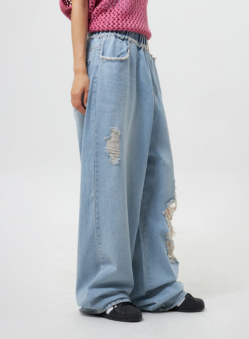 Oversized Ripped Jeans CY324 in light blue, side view on model, revealing frayed destroyed rips and banded elastic waistband detail on wide-leg light-wash denim.