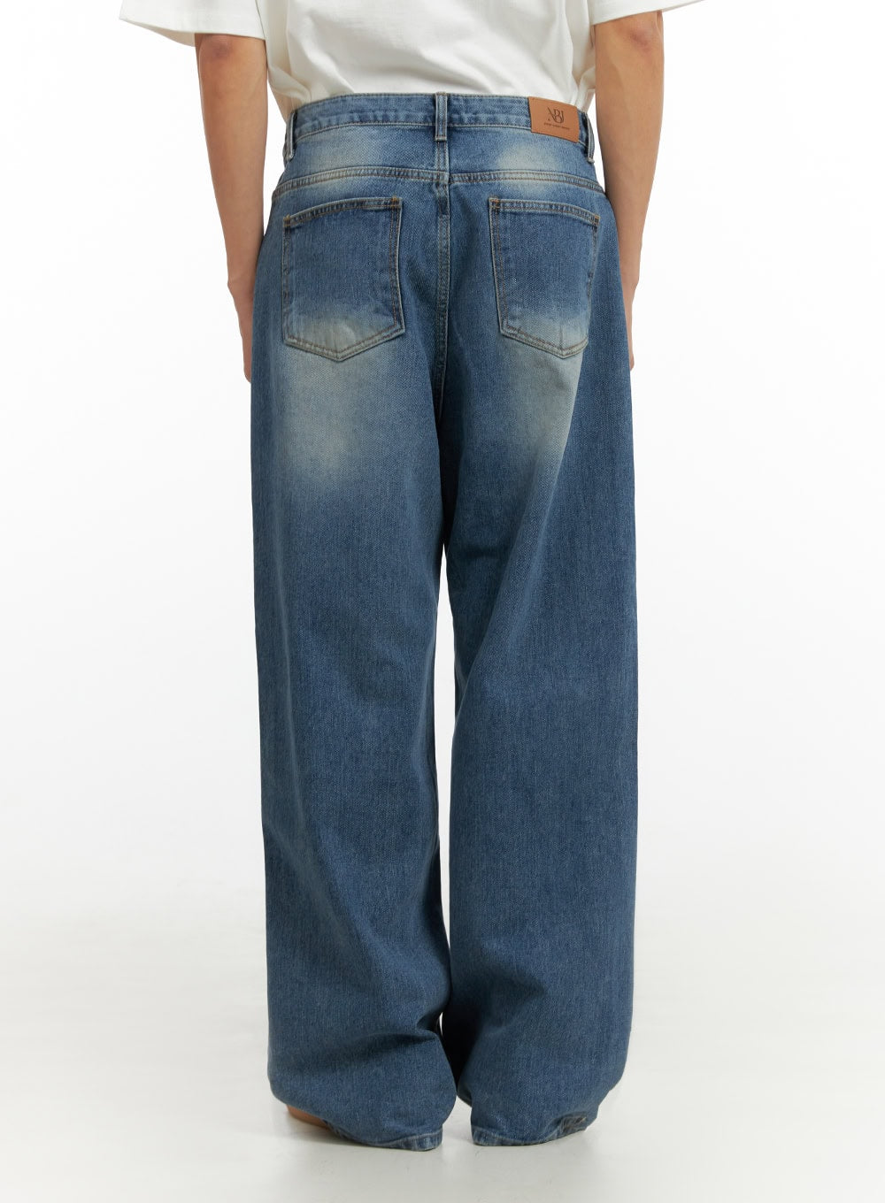 Men's Solid Baggy Jeans IU419 in blue, back view on model, displaying dual back pockets with fading, LEWKIN leather logo patch at waistband, wide baggy cut denim.