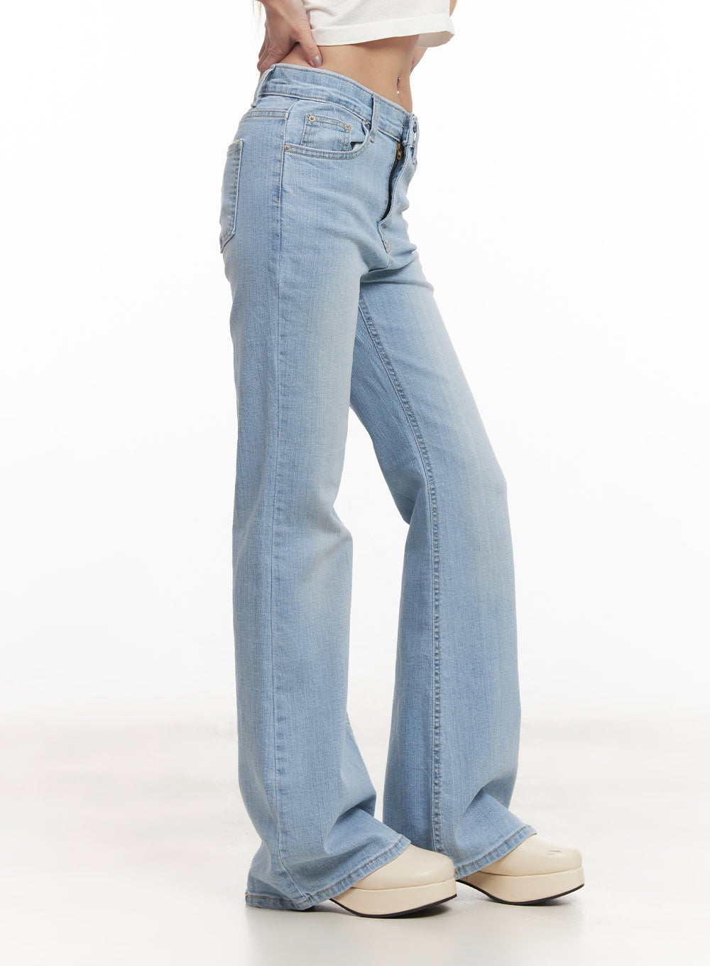 Suzy Slim-Fit Bootcut Jeans CM505 in light blue, pure side view on model, showing slim thigh and bootcut flare silhouette, washed cotton-spandex denim, with white platform clogs.