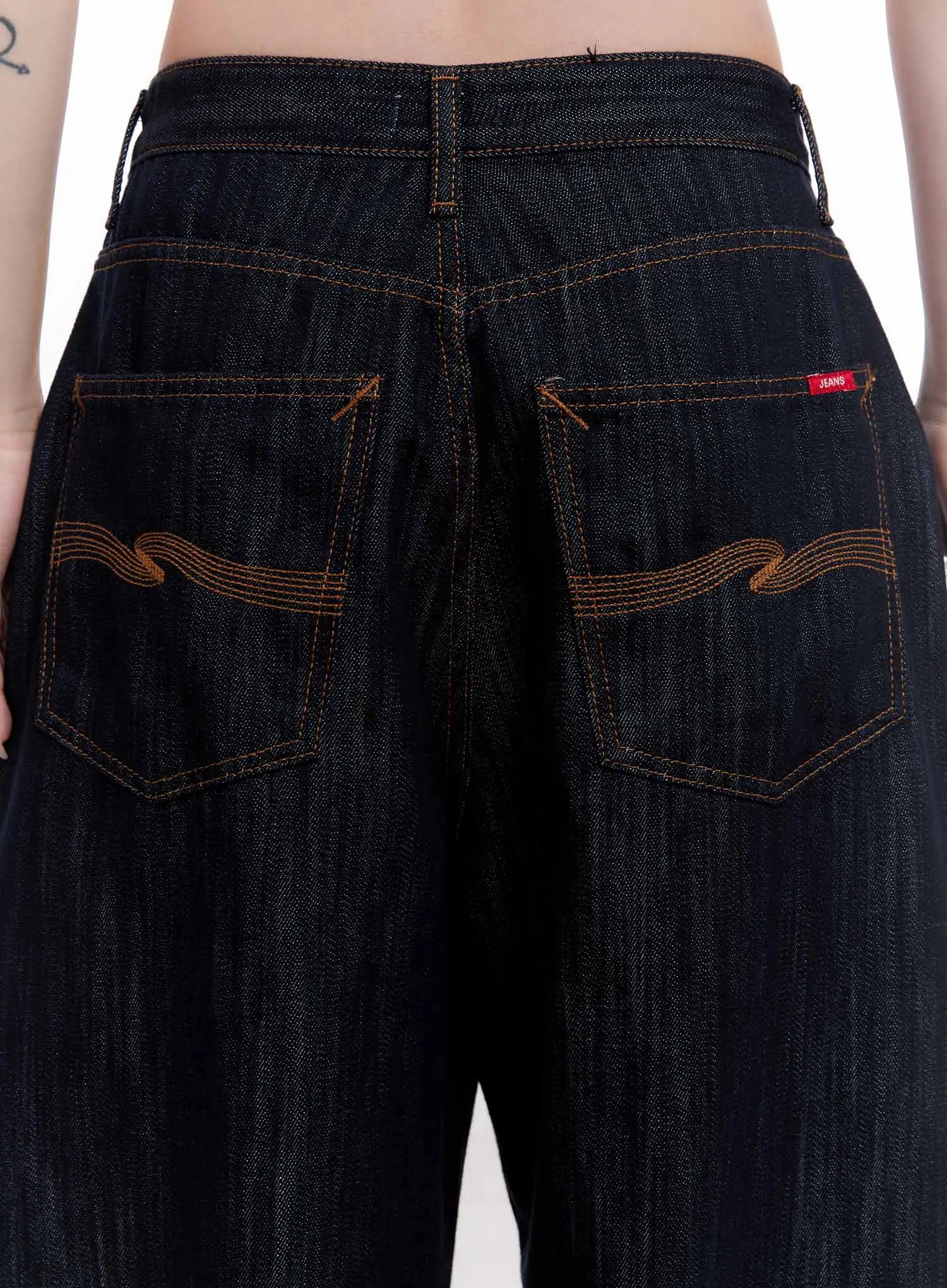 Haewon Dark Washed Baggy Jeans CS530 in dark blue, back close-up detail on model, showing back pockets with decorative wave amber embroidery stitching and red woven label tab.