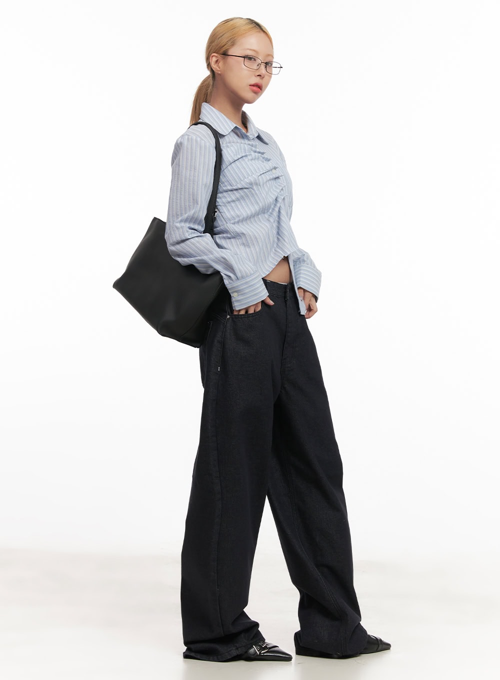 Julianna Baggy Jeans CM505 in black denim, side full-body on model, relaxed wide-leg drape floor-length, styled with blue striped shirt and oversized black tote bag.