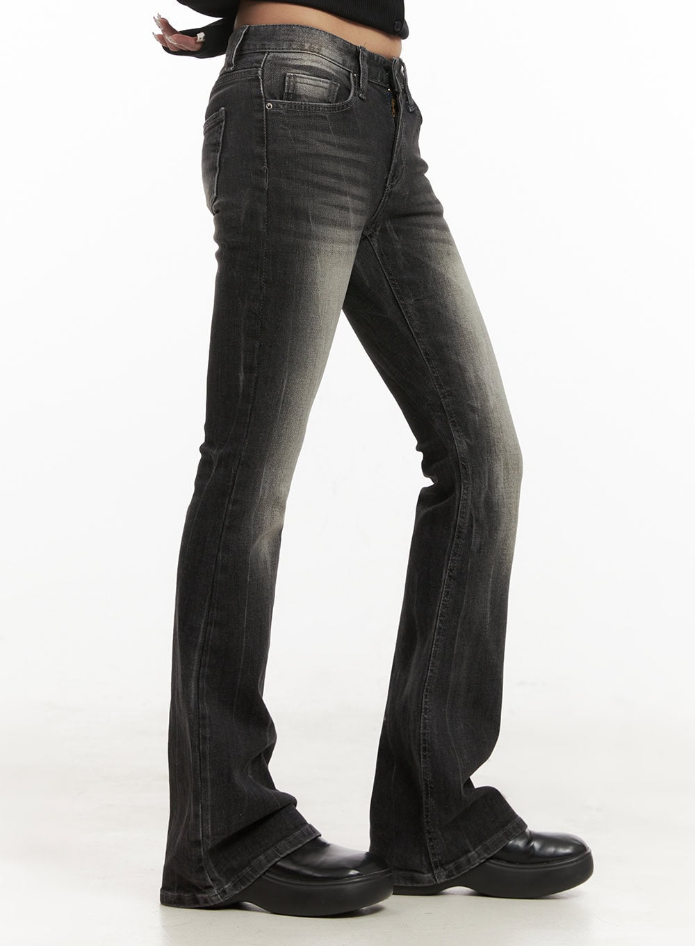 Georgina Low-Rise Flared Jeans CJ507 in black, side close-up on model, washed cotton-spandex denim with faded grey tones, slim thigh tapering into wide flare, low-rise waistband and coin pocket visible.