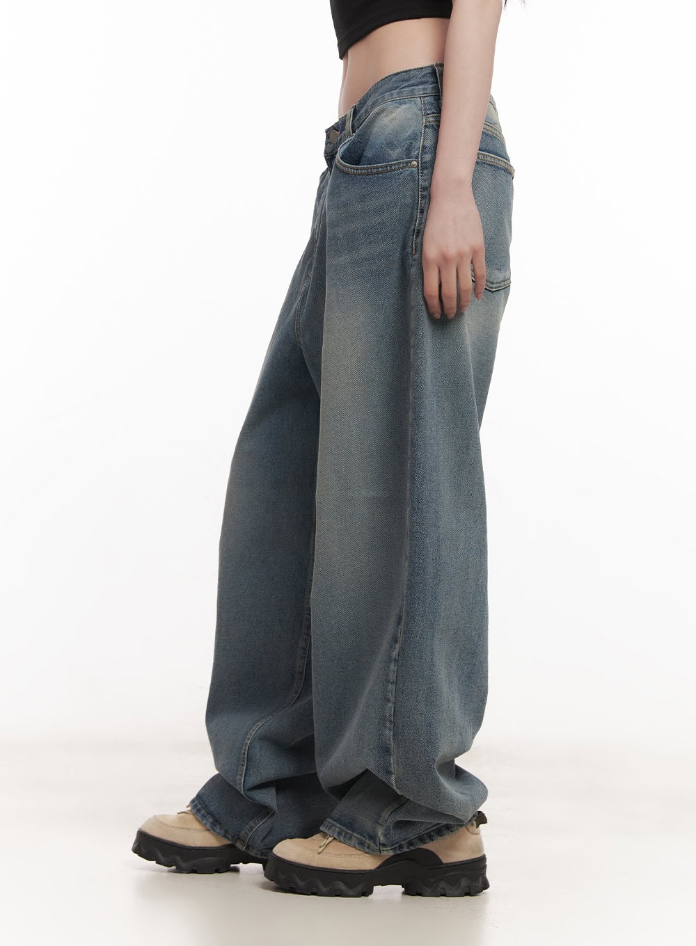 Shelly Washed Baggy Jeans CM518 in blue, side view on model, low-rise washed denim with exaggerated wide leg and subtle fading, paired with black crop top and chunky sneakers.
