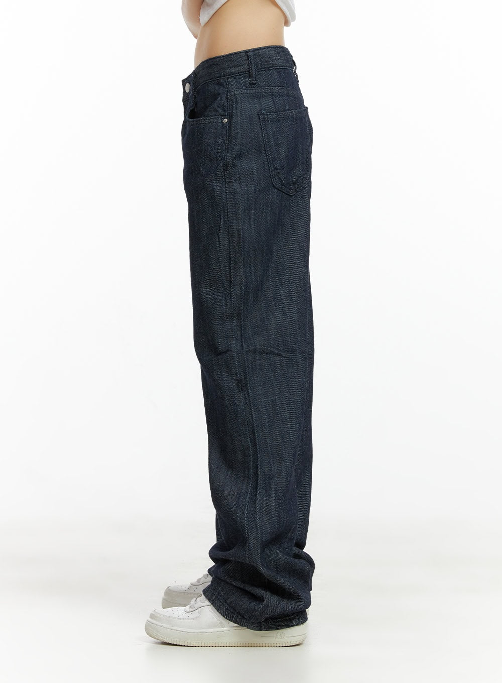 Low Waist Loose Fit Baggy Jeans CL403 in dark blue, side detail close-up on model, low-rise waistband and coin pocket detail, wide-leg pooling at ankle over white sneakers.