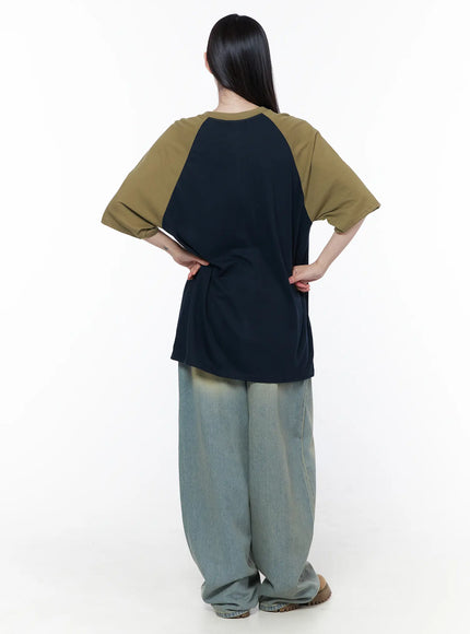 Casual Loose Fit Graphic Tee CU519 in dark blue, back view on model hands on hips, clean navy back panel with olive raglan sleeves, relaxed drop-shoulder fit, paired with wide-leg jeans.