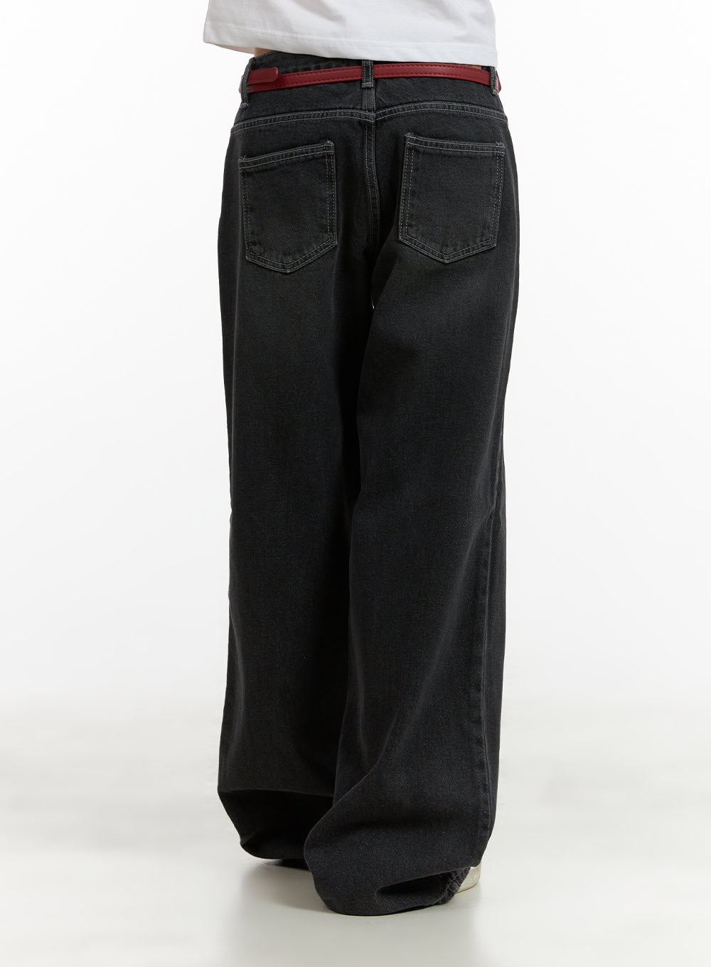 Low Rise Baggy Jeans CU410 in black, back view close-up on model, washed denim with dual back patch pockets and wide-leg silhouette, red belt detail visible.