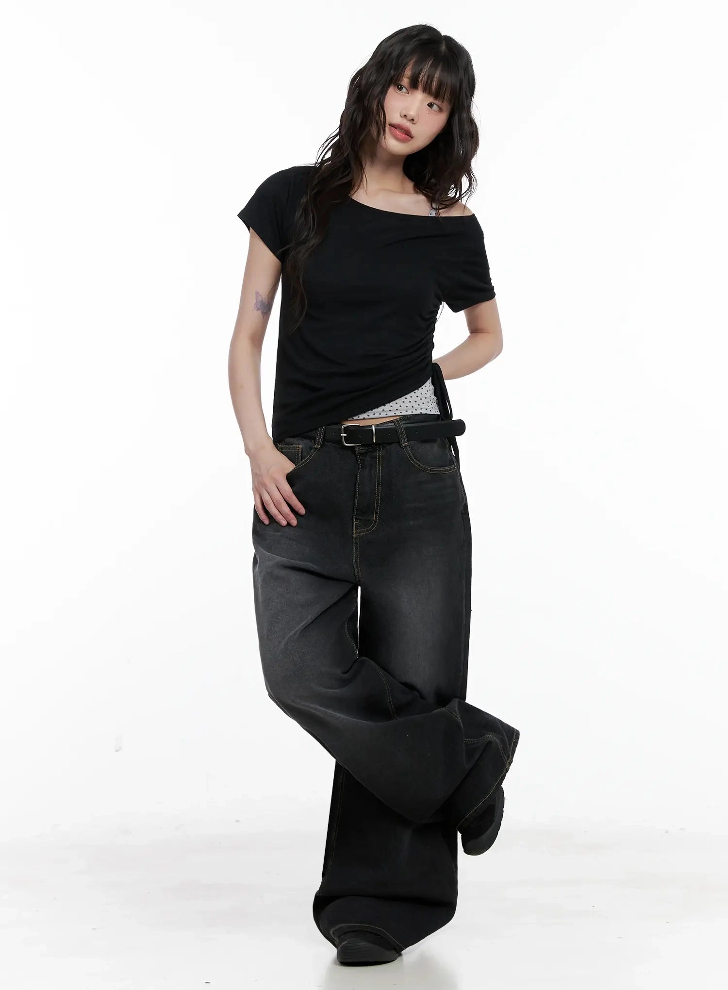 IU Vintage Black Baggy Jeans IL528 in black, full-body front shot on model with hand in pocket, washed wide-leg denim, belted low rise, paired with black off-shoulder crop top.