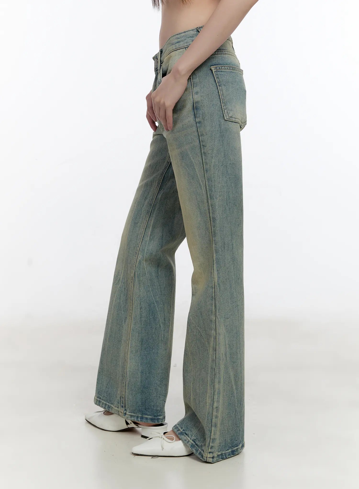 Roa Vintage Blue Flared Denim Jeans CL504 in blue, side view on model, showing low-rise waistband, back pocket placement, subtle flare from knee down, washed cotton denim, white ballet flats.