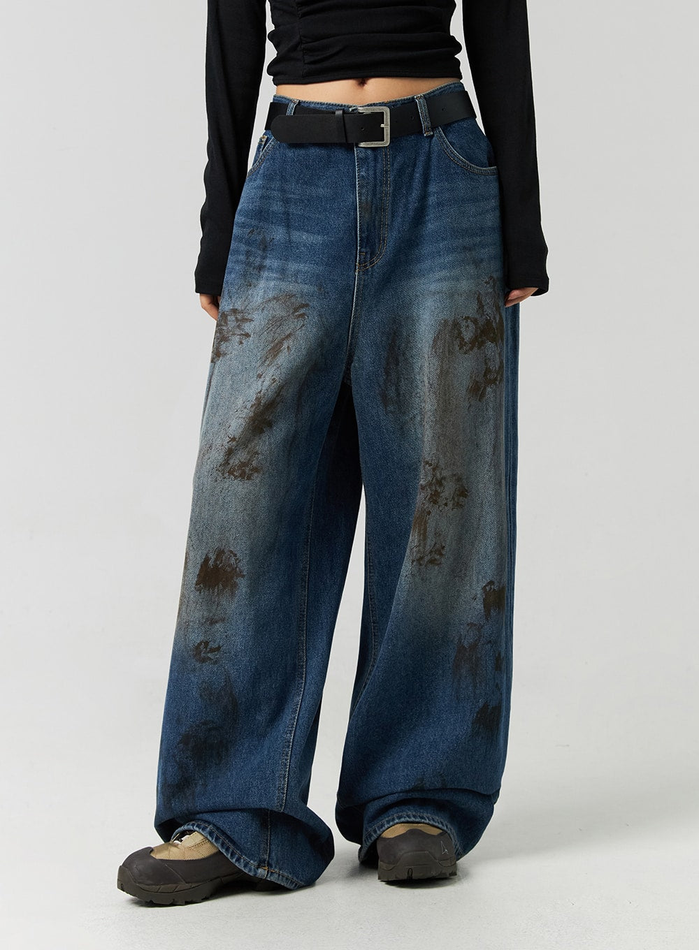 Street-Style Wide Fit Washed Jeans CO323 in Blue, front mid-shot on model with black long-sleeve crop top and belt, wide fit high-rise denim showcasing bold brown washed distress across thighs.
