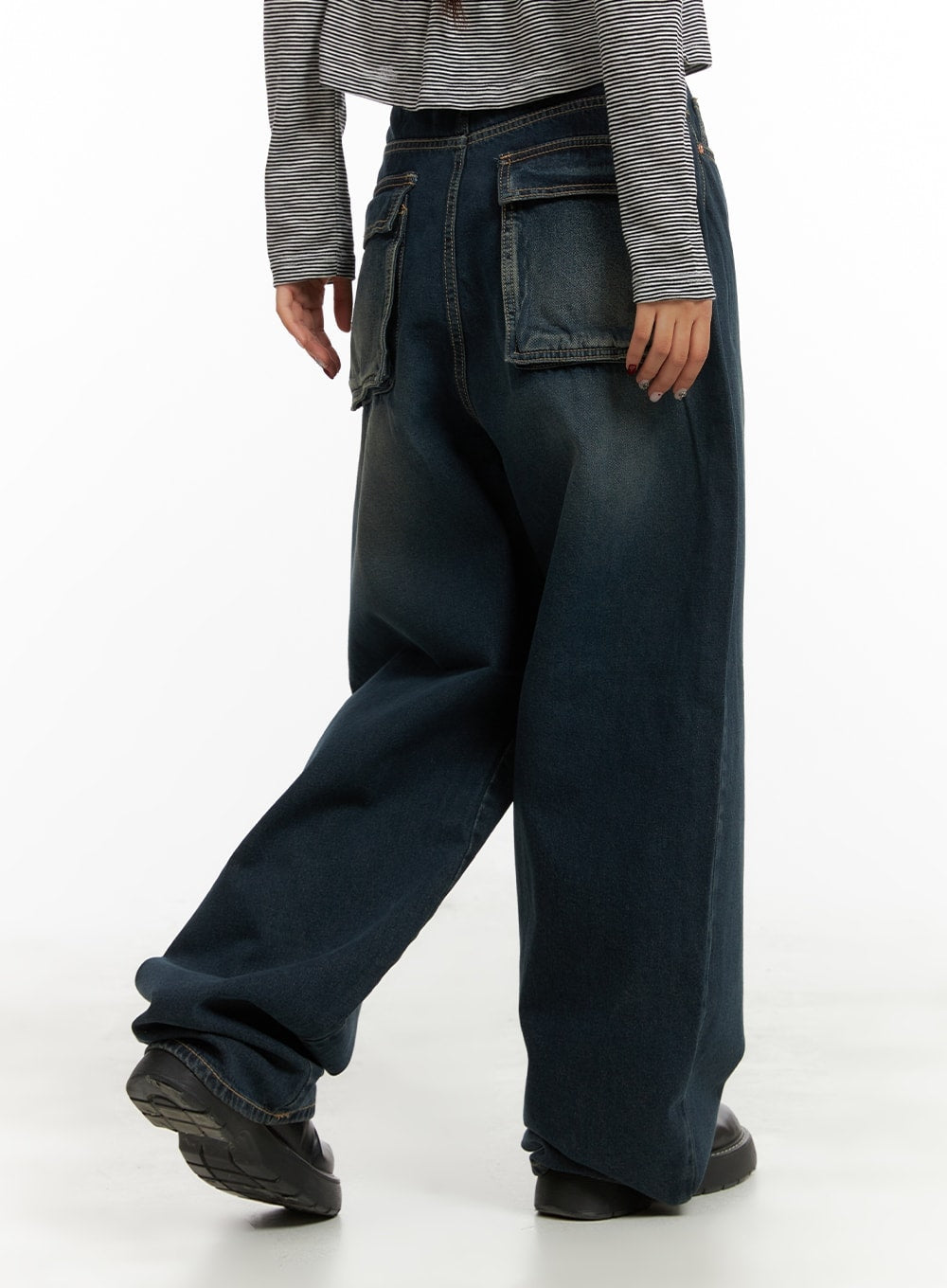 Washed Denim Baggy Jeans CA415 in blue, back three-quarter angle on model walking, large utility patch pockets, washed cotton denim, voluminous wide leg, styled with striped top and chunky shoes.