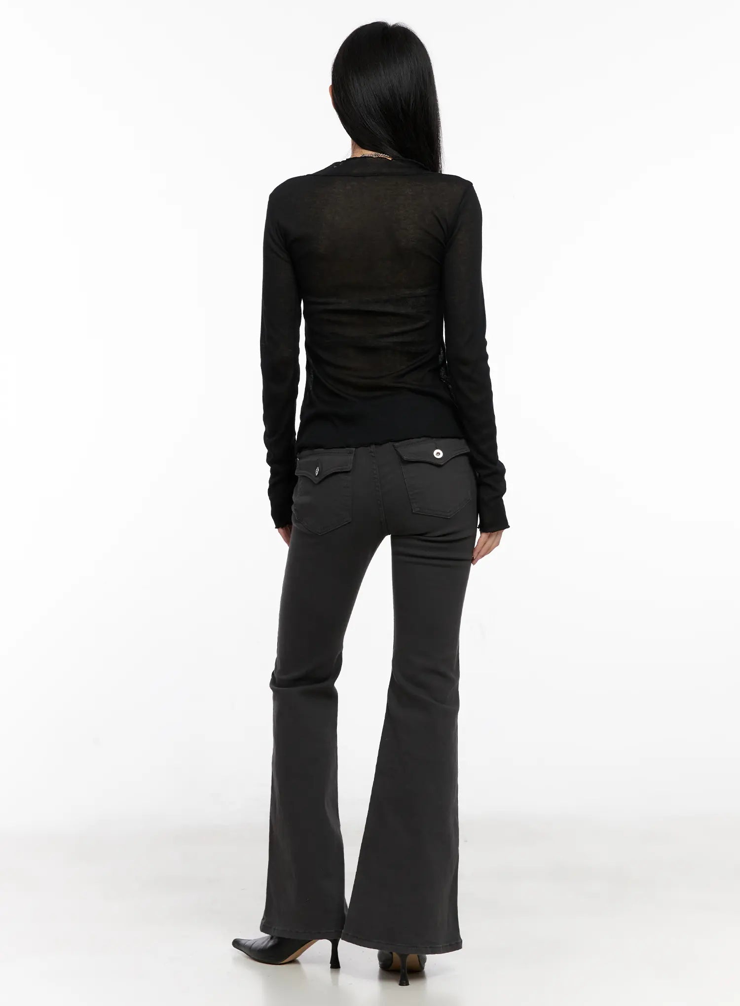 Addie Chic Flared Jeans CG522 in dark gray, full-length back view on model, flared bootcut hem, two flap back pockets with snap buttons, slim fit through hips, worn with black top.