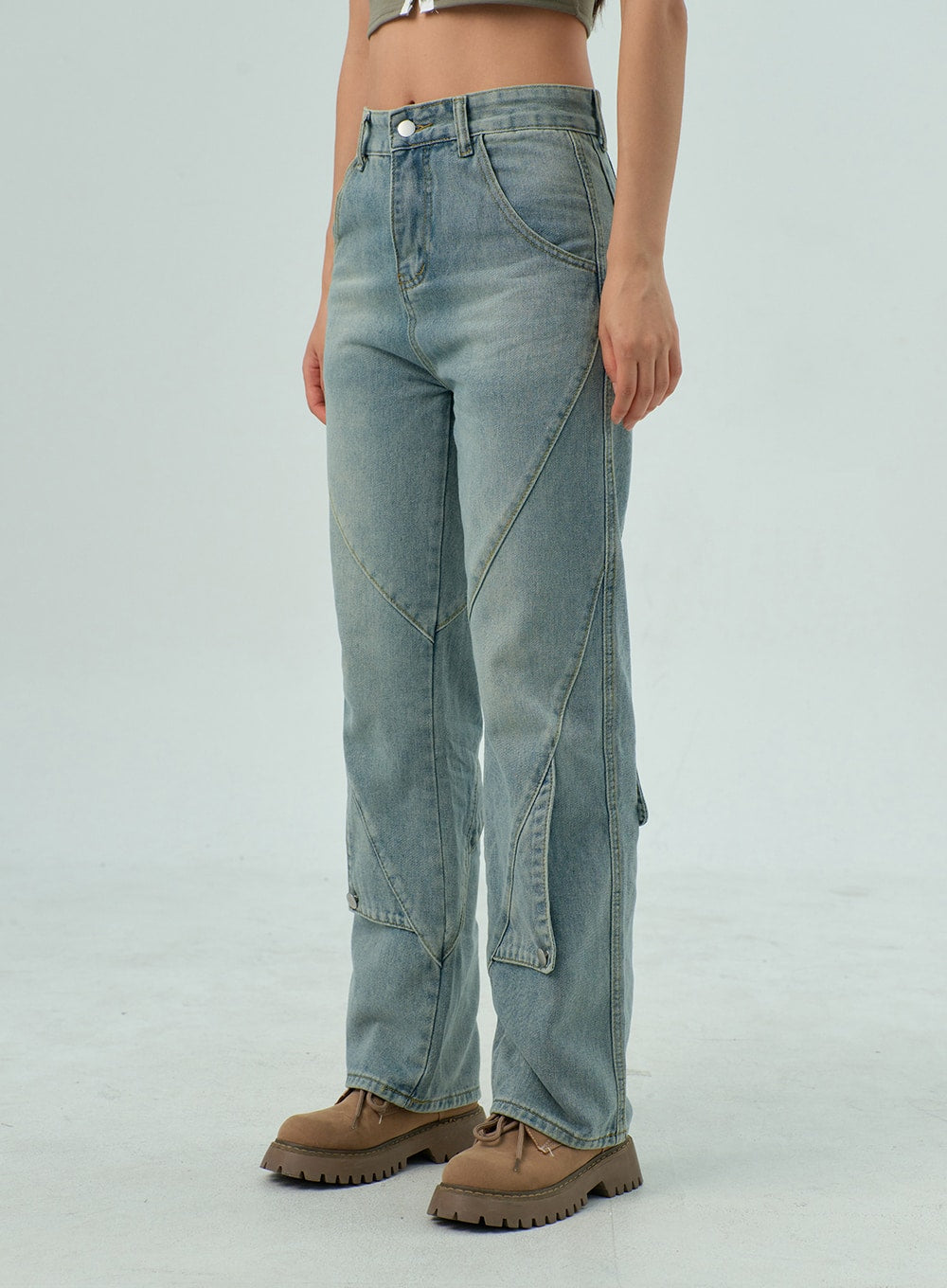 Straight Leg Jeans CY330 in light blue wash, front three-quarter side close-up from waist to hem, washed cotton denim with angular panel seams and snap button at lower leg, tan boots.