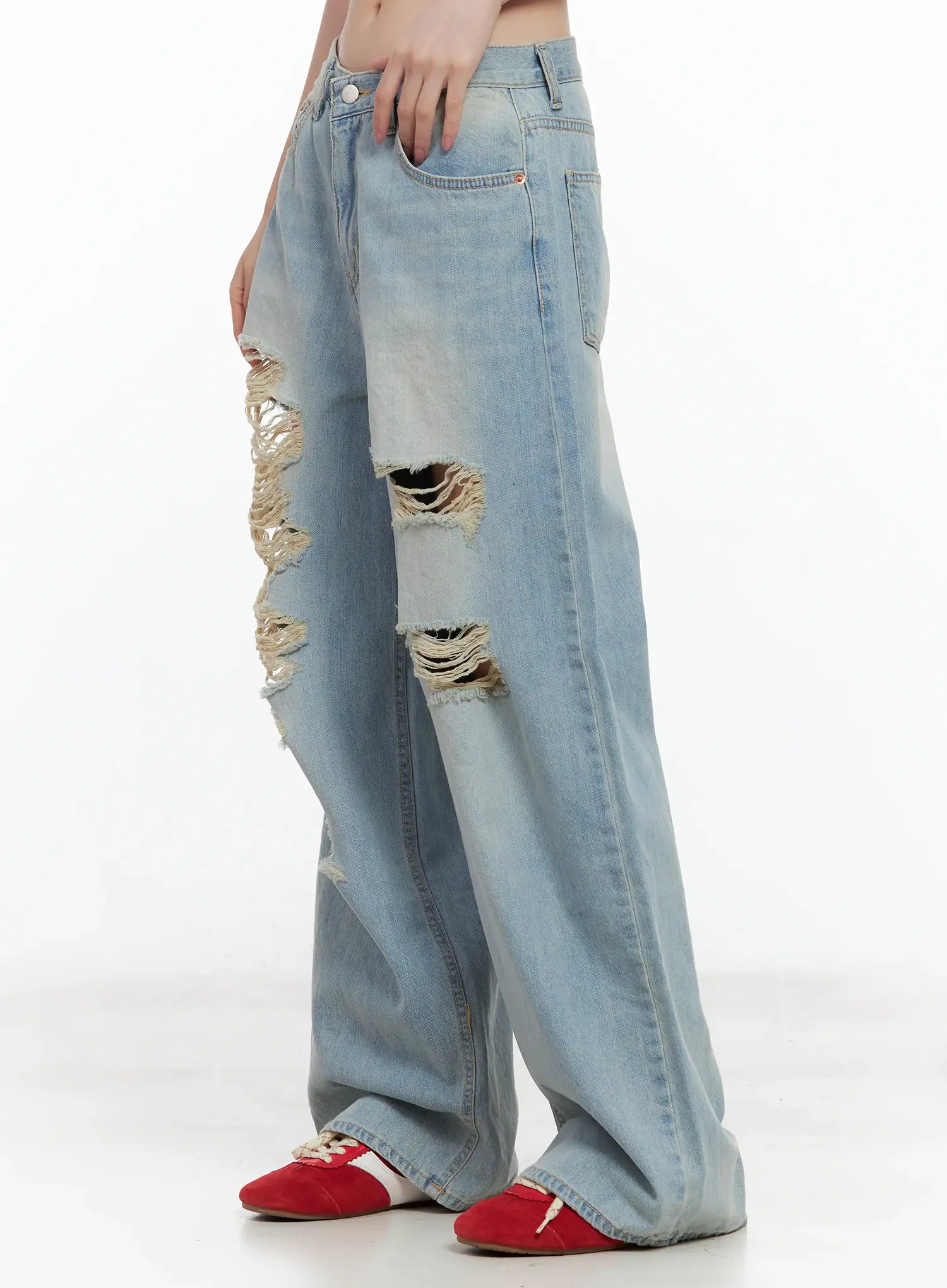 Gyuri Dirty-Wash Distressed Wide Jeans CU530 in blue, side view on model, wide-leg silhouette with frayed rip detail at thigh, dirty-wash fade, red sneakers.