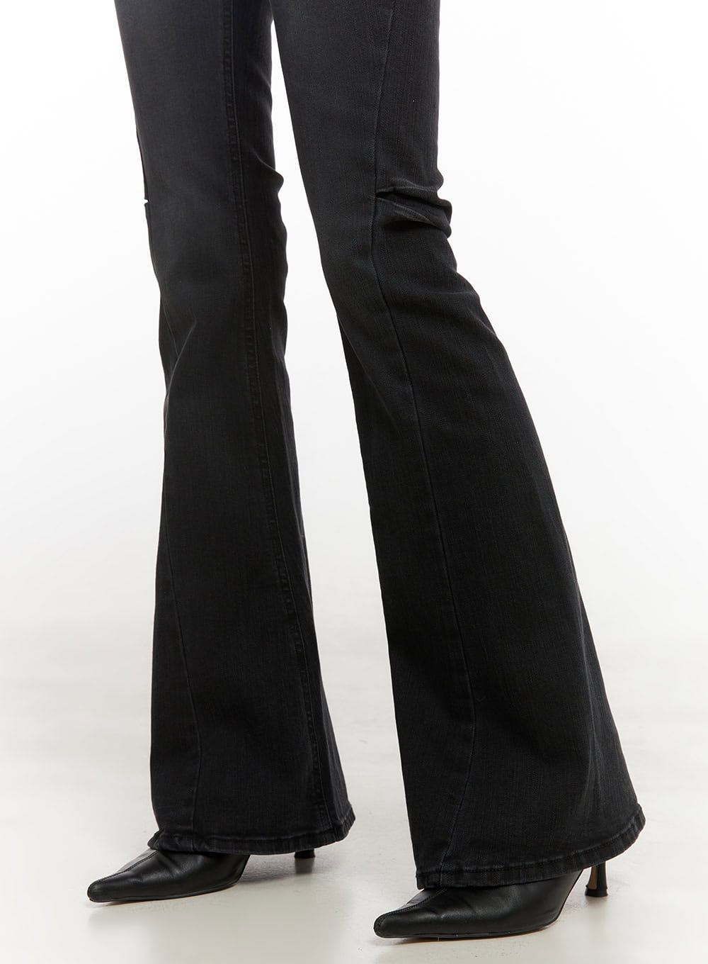 Belle Slim Fit Flared Jeans CD410 in black, lower-leg close-up on model, wide flared hem pooling over black pointed kitten-heel boots, washed denim construction.