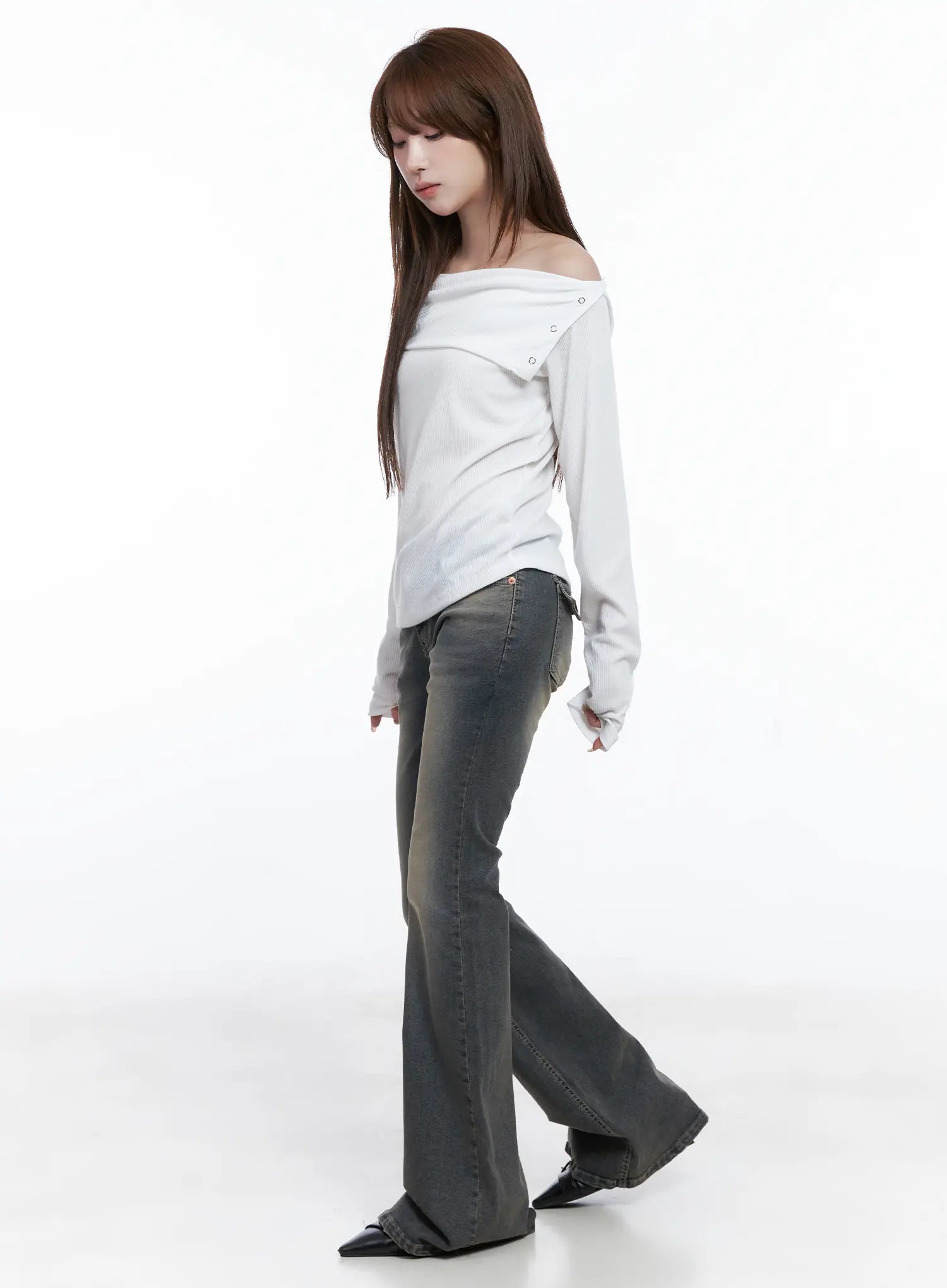 Sumin Low-Rise Flare Hip Pad Jeans CG529 in gray, three-quarter side view on model walking, styled with white off-shoulder ribbed top, flare leg and washed finish visible.