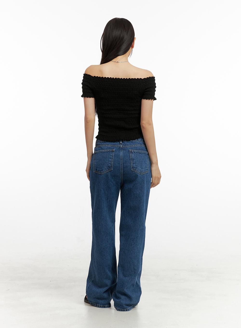 Blue Wide-Leg Jeans OU407 in blue, back full-body view on model, showing two back patch pockets and wide straight leg in washed cotton denim, styled with black off-shoulder top and sandals.