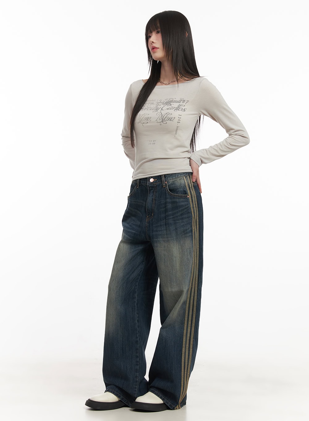 Daisee Striped Wide-Leg Jeans CF518 in dark blue, front three-quarter view on model, wide-fit washed denim with gold triple side stripes, styled with beige graphic tee and white platforms.