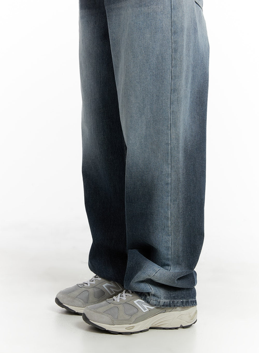 Recycled Wide Baggy Jeans (Unisex) CM425 in dark blue, lower-leg detail shot on male model, extra-wide leg hem pooling over grey New Balance sneakers, washed cotton denim fabric visible.