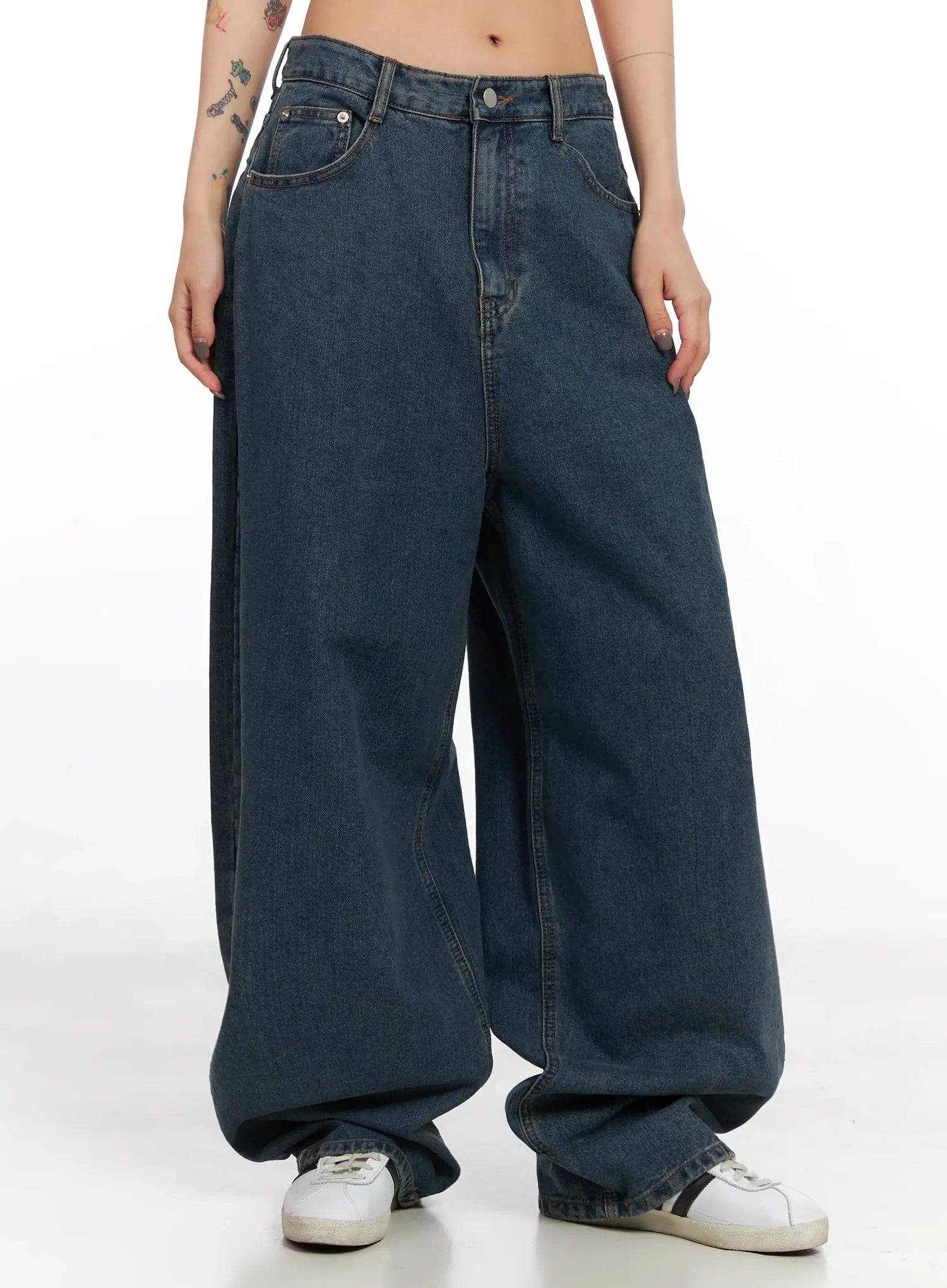 Aleena Mid-Wash Baggy Jeans IN528 in dark blue, front mid-shot on model, hands at sides, highlighting low-rise waistband and oversized ballooned leg drape, styled with white sneakers.
