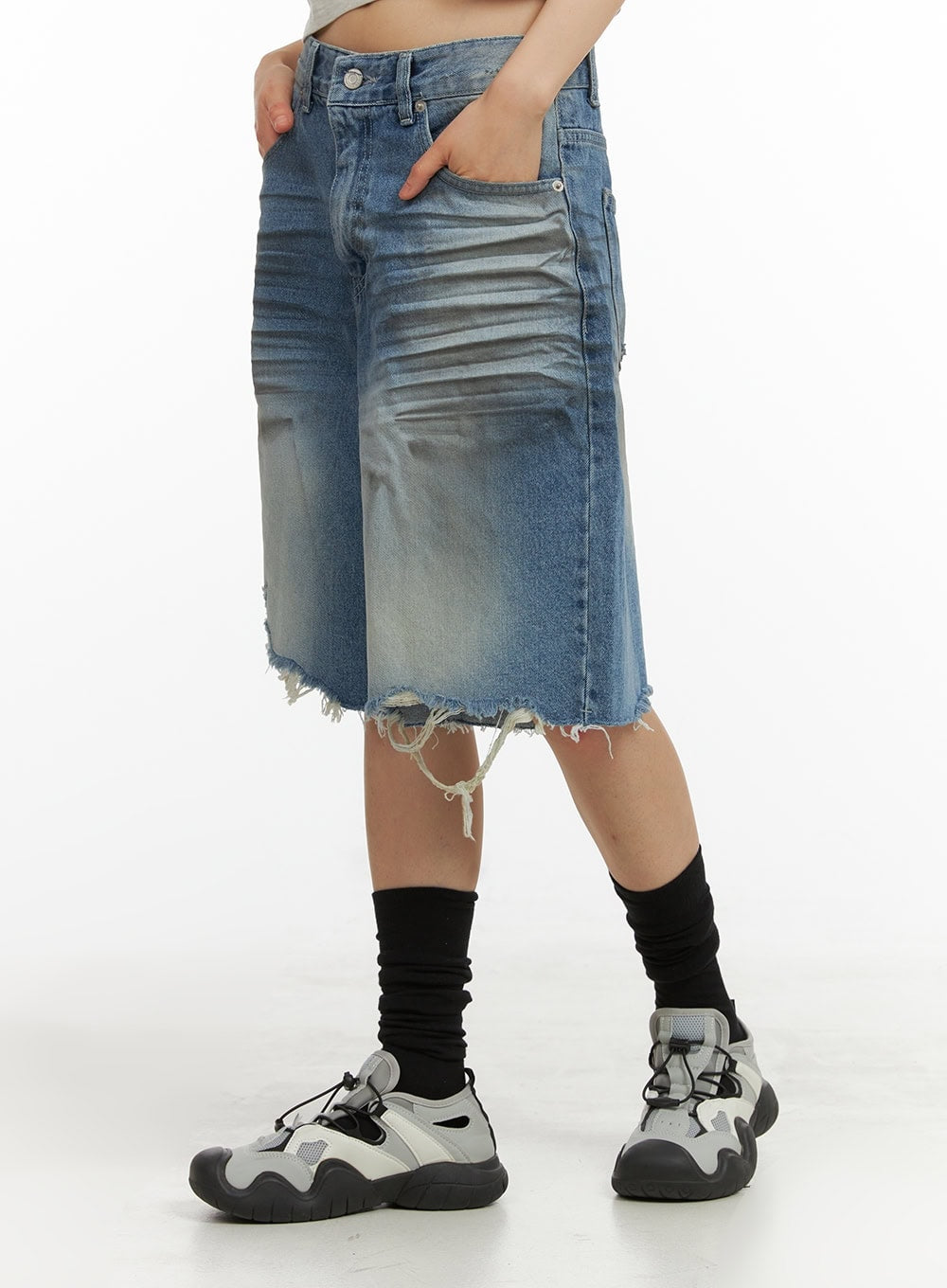 Destroyed Hem Bermuda Jorts CY414 in blue, side close-up on model, wide-fit cotton denim highlighting washed fading, hanging frayed threads at destroyed hem, hand resting in pocket.