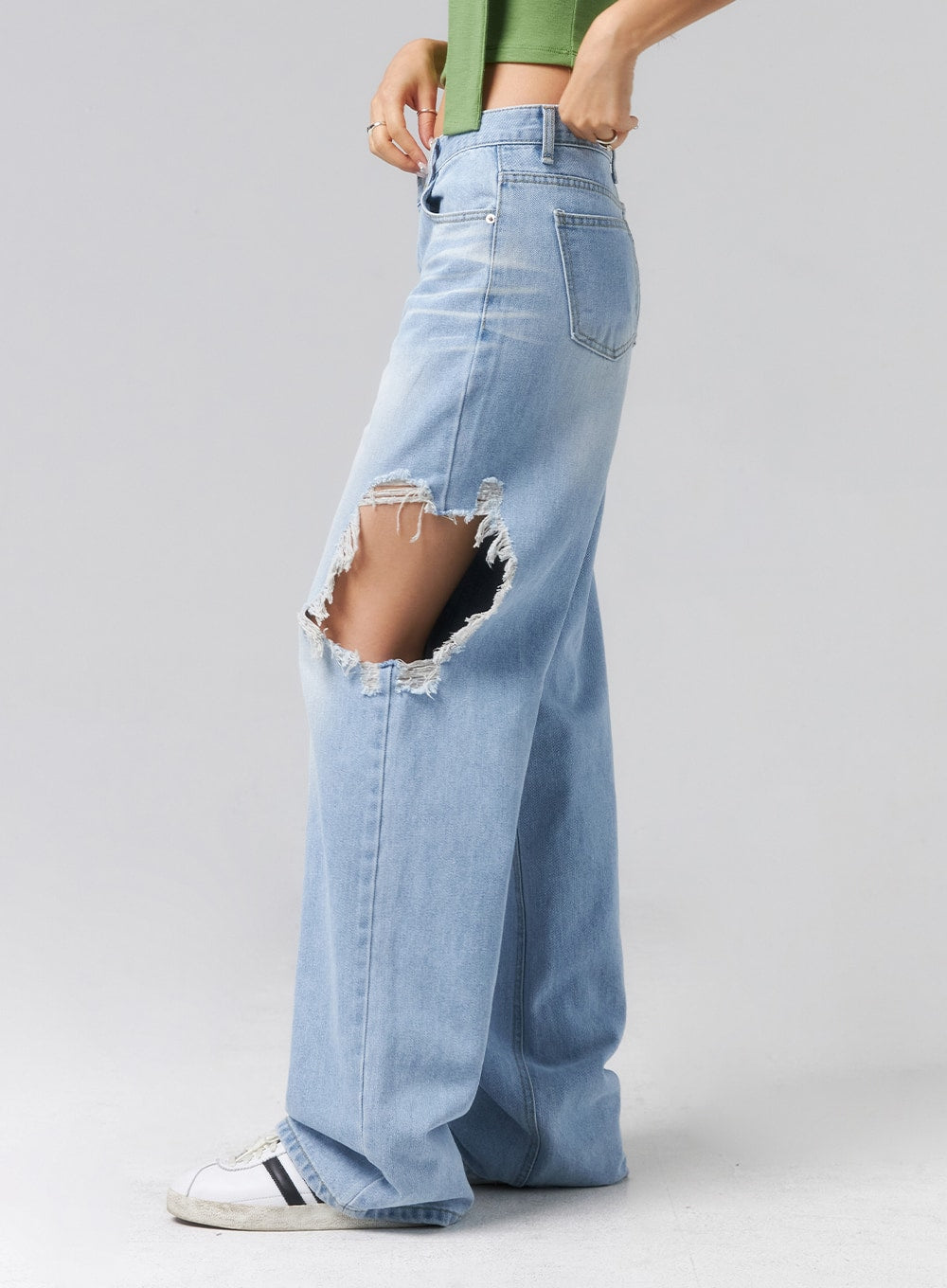 Ripped Side Jeans CL320 in light blue, side close-up on model, showing large destroyed rip at outer thigh with frayed edges, wide-leg cotton denim with five-pocket construction.