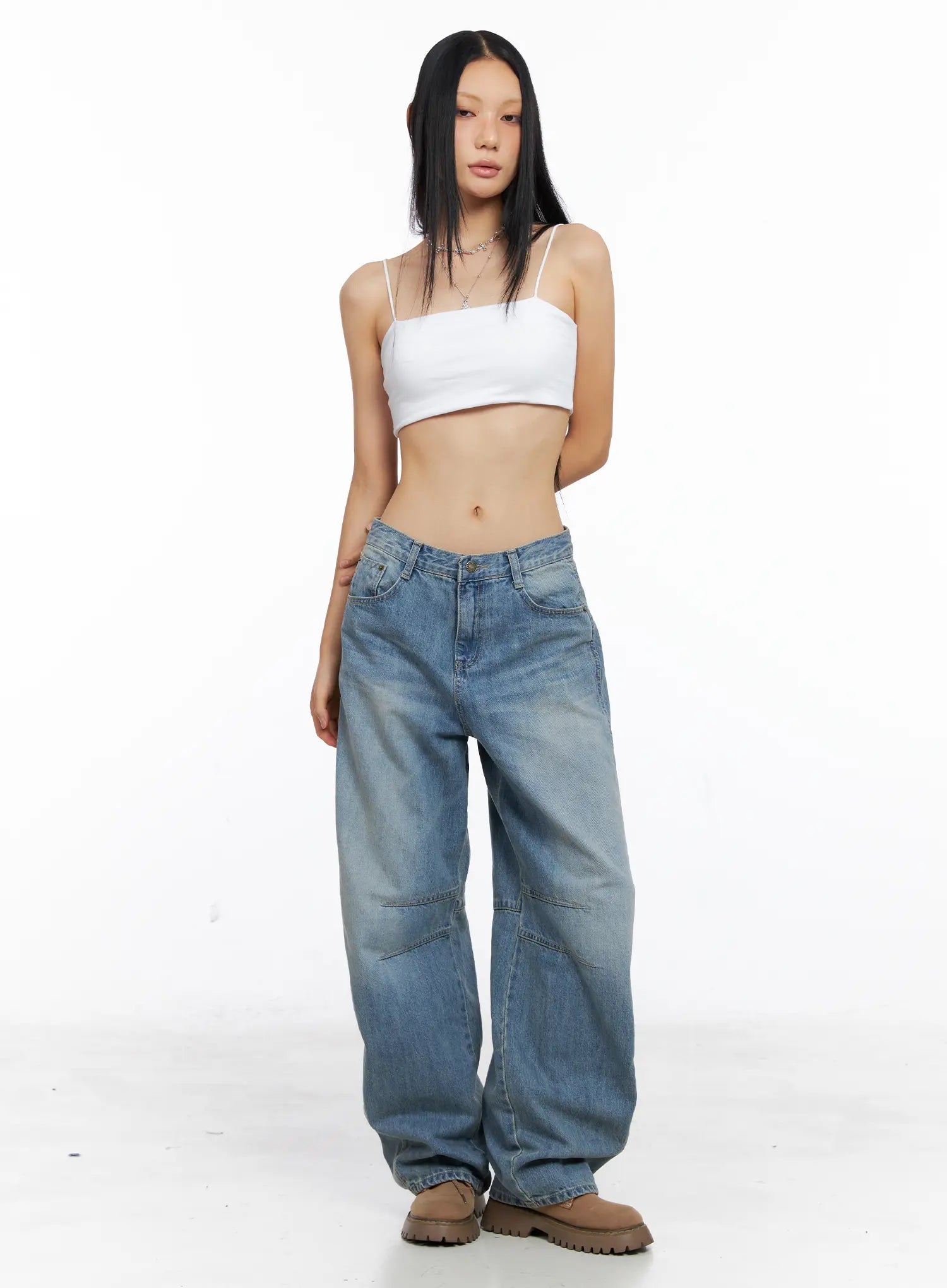 Dakota Relaxed Fit Vintage Wash Jeans CS511 in blue, full-length front studio shot on model standing straight, relaxed wide-leg silhouette with vintage wash and knee-panel stitching, white cami top, tan boots.