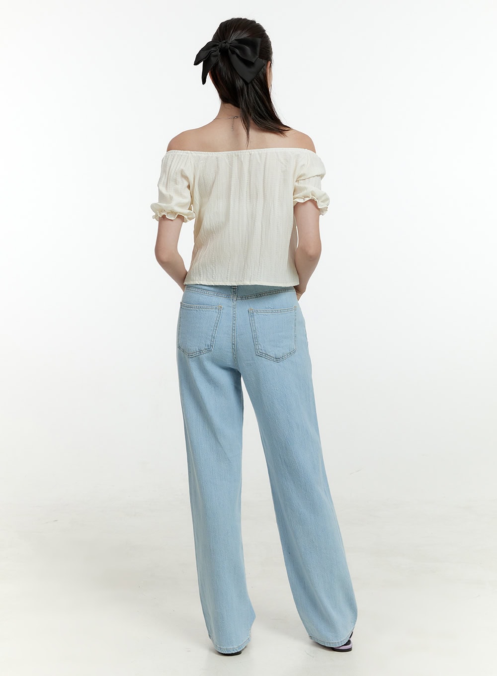Ava Light Washed Straight Jeans OL430 in light blue, back full-length view on model, wide straight leg, back patch pockets visible, light washed denim, paired with ivory off-shoulder puff-sleeve top.