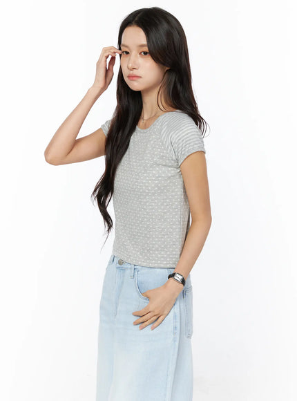 Polka Dot Striped Crop Tee CU522 in gray, side view on model with hand raised, showing slim fitted crop silhouette, polka dot front and striped sleeve detail, with light jeans.