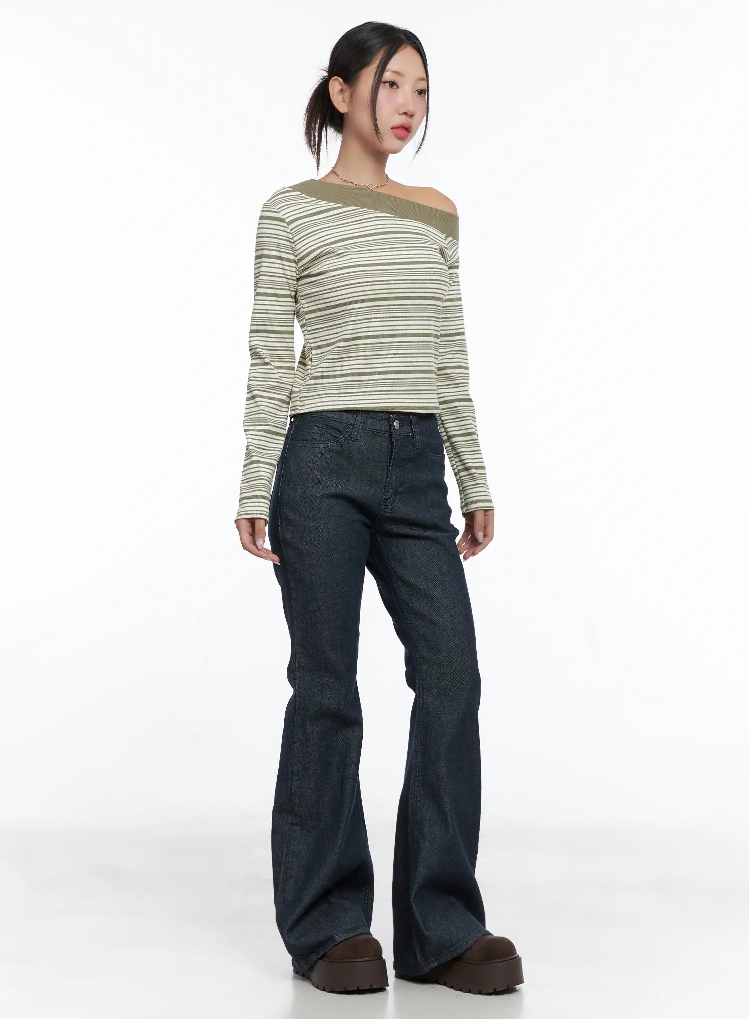 Kinley Flare Jeans CS502 in dark indigo, three-quarter front view on model, flare hem at floor length, normal fit through hip, styled with olive stripe top.