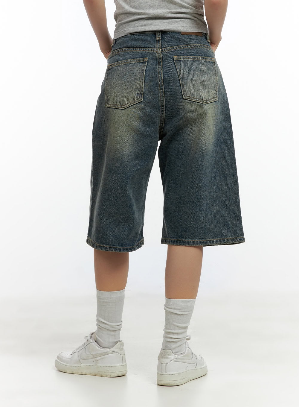 Slim Fit Bermuda Jorts CL410 in blue, back view on model, wide-leg washed denim with two back patch pockets and vintage yellow-fade wash, worn with white sneakers.