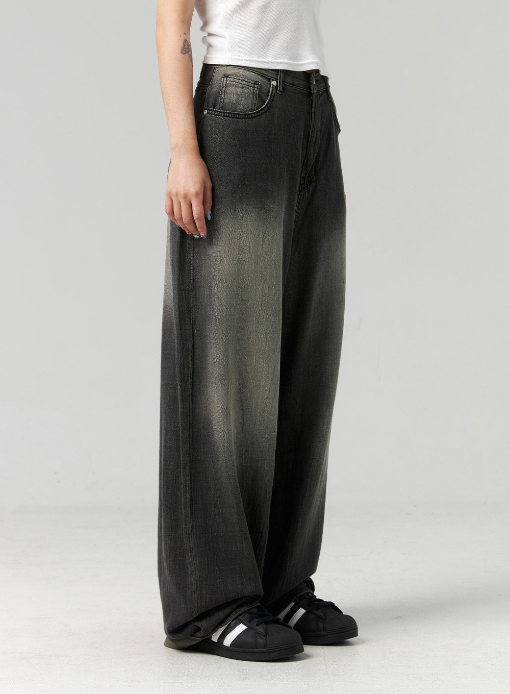 Baggy Jeans CL321 in washed dark grey, side view close-up from hip to hem on model, wide-leg silhouette with faded grey gradient wash, voluminous denim leg, white tee tucked.