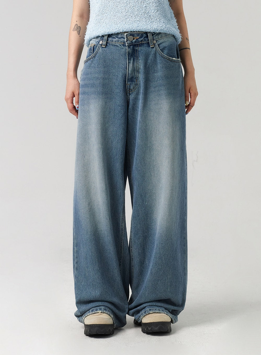 Baggy Jeans CL313 in washed blue, mid-section close-up on model, highlighting wide-leg fit, five-pocket construction, button fly, and sun-faded washed denim texture.