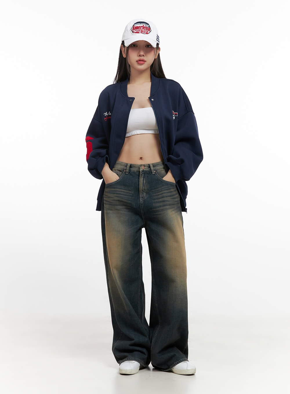 Bryana Cotton Comfort Wide Leg Jeans CN419 in dark blue, full-body front editorial shot on model, low-rise washed wide leg denim styled with open navy bomber, white crop top, and logo cap.