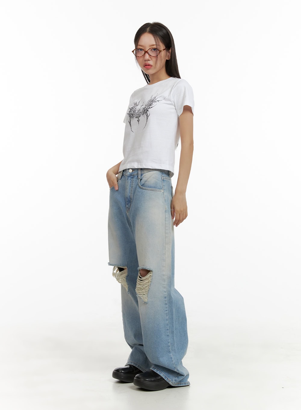 Urban Washed Ripped Baggy Jeans CU405 in Blue, three-quarter side full-body on model, grunge silhouette with oversized wide leg and destroyed knee, paired with white graphic crop tee.