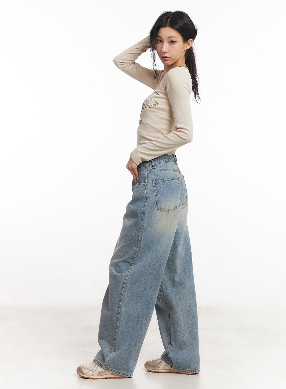 Devyn Wide-Leg Jeans CA503 in blue, side-back view on model, washed denim highlighting back pockets and wide-leg sweep, styled with beige crop top and sneakers.