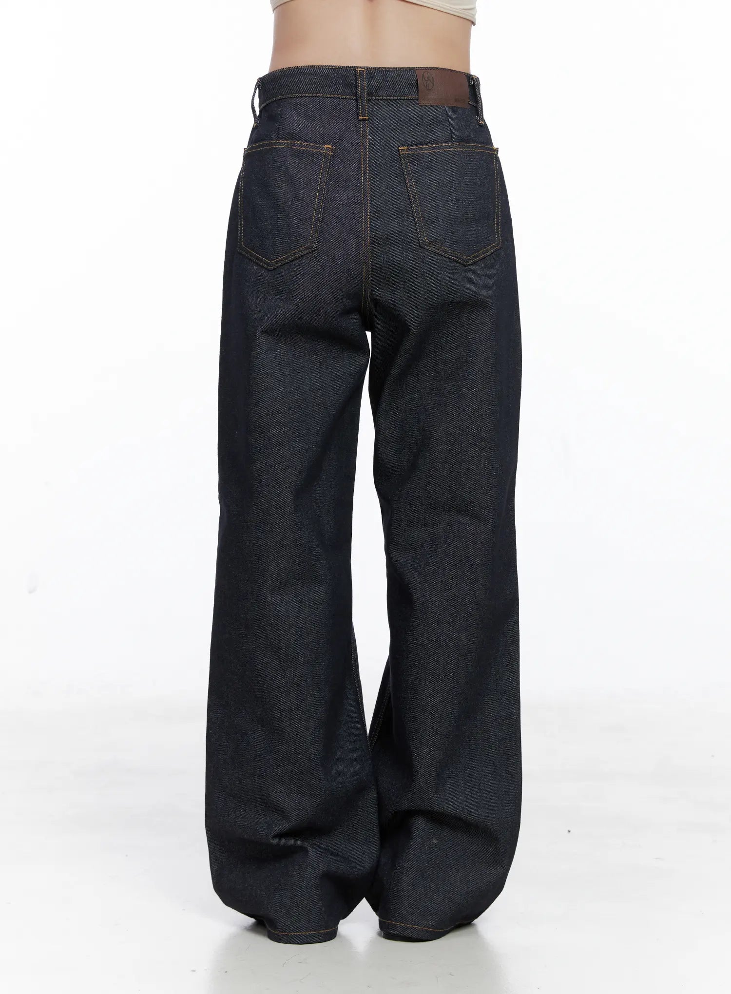 Reyna Non-Fade Relaxed Jeans CS519 in dark blue, back product shot on model, showing dual back pockets with contrast gold stitching, brown leather waistband patch, and wide relaxed leg in raw cotton denim.