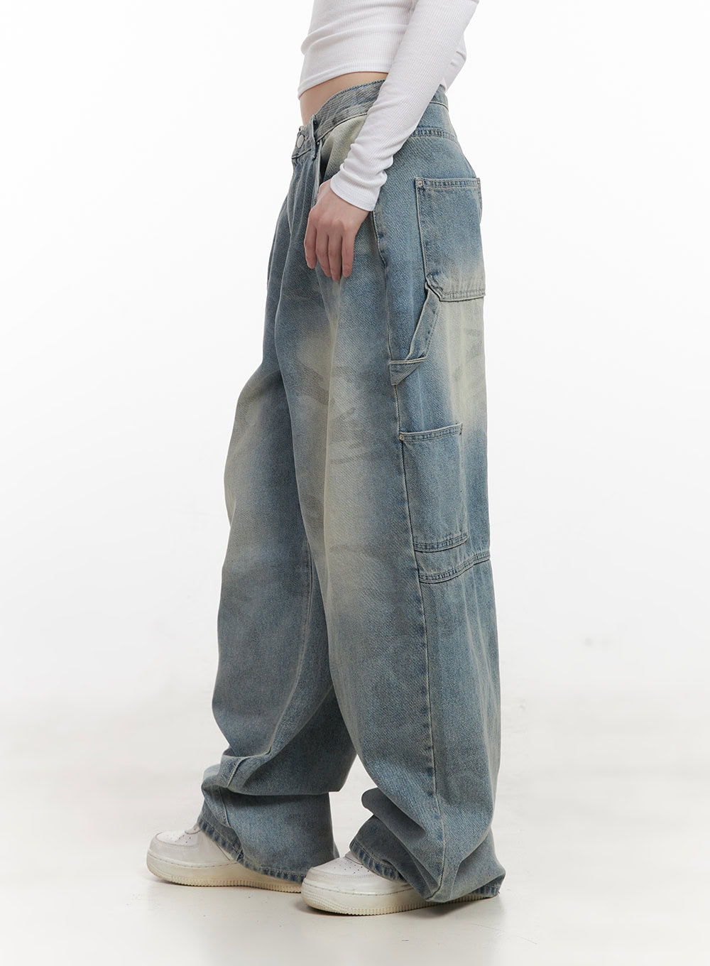 Abigail Camo-Print Carpenter Baggy Jeans CJ528 in blue, side full-length shot on model, carpenter pockets on thigh, washed camo wide-fit denim pooling at ankles, white sneakers.