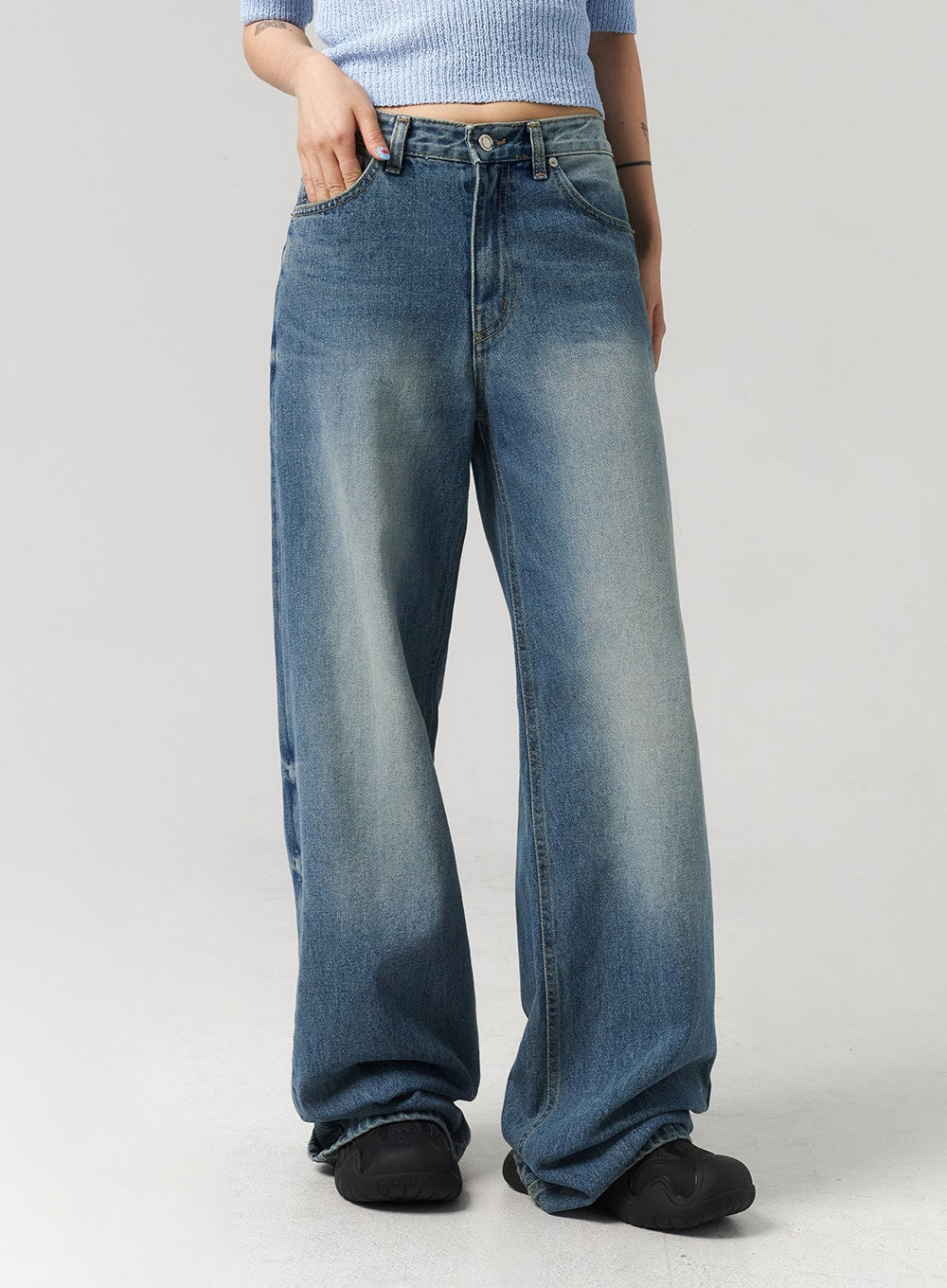 Mid-Wash Baggy Jeans CL312 in mid-wash blue, front mid-shot close-up on model, low-rise five-pocket construction, wide baggy leg with streaky fade wash and excess length bunching at ankle.