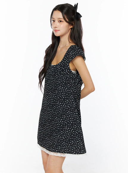 Floral Lace Trim Mini Dress CU522 in black, three-quarter side-back view on model, cap sleeves, gathered waist, floral ditsy print, white lace trim peeking at hem.