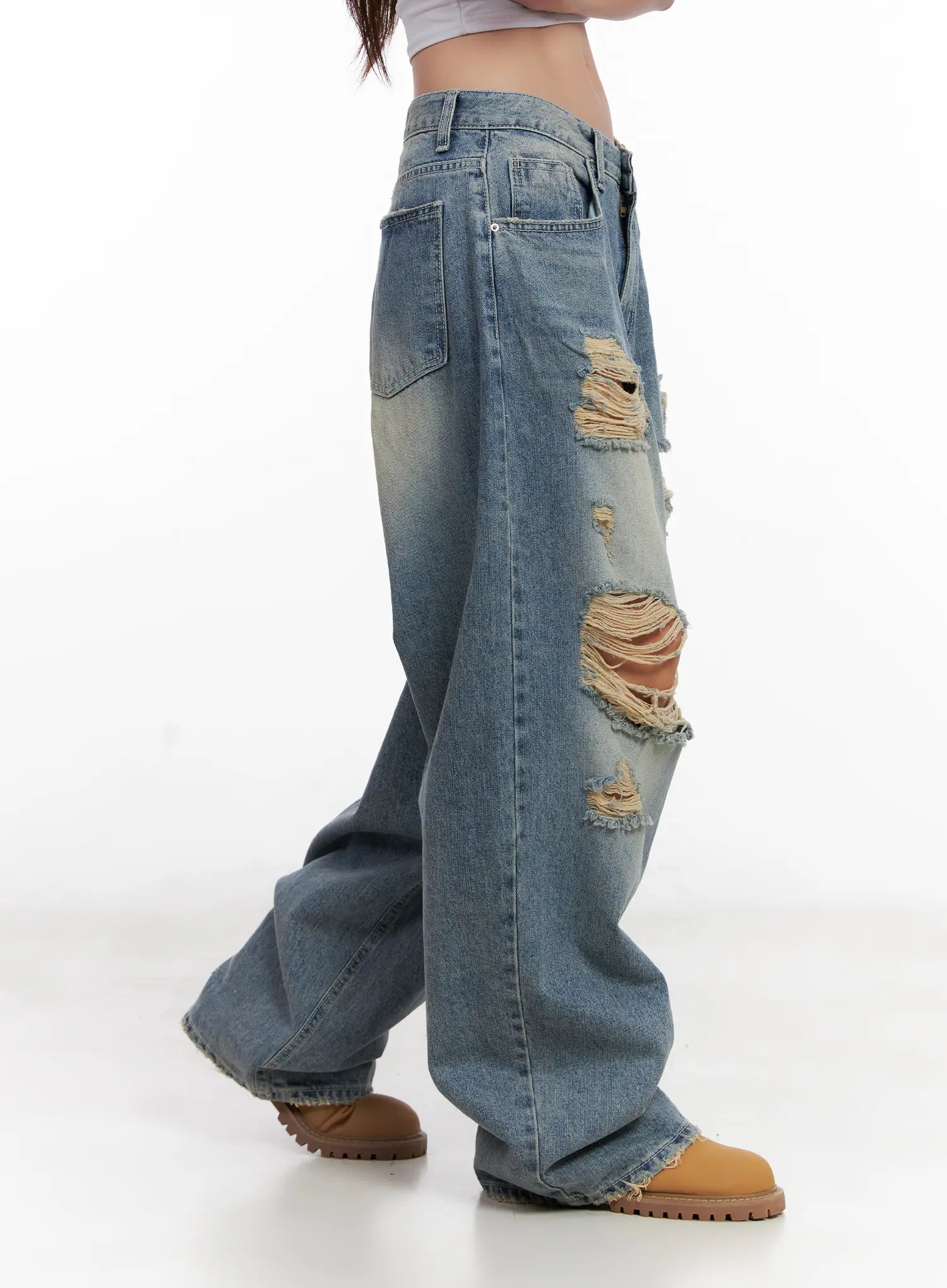 Manon Washed Distressed Wide Jeans CL518 in blue, side walking-pose shot on model, mid-thigh destroyed openings with heavy fringe detail visible, long wide-leg drape in motion.