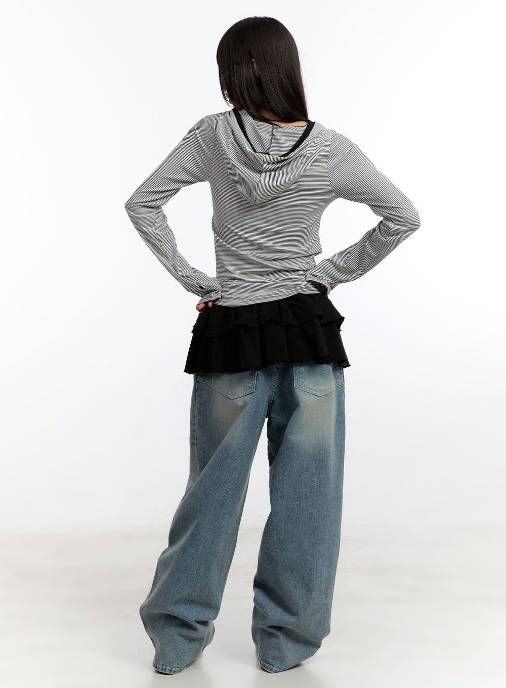 Jillie Washed Baggy Jeans CA508 in blue, back full-length view on model, washed baggy denim showing dual back pockets with V-stitch detail, paired with striped hoodie and ruffle skirt overlay.