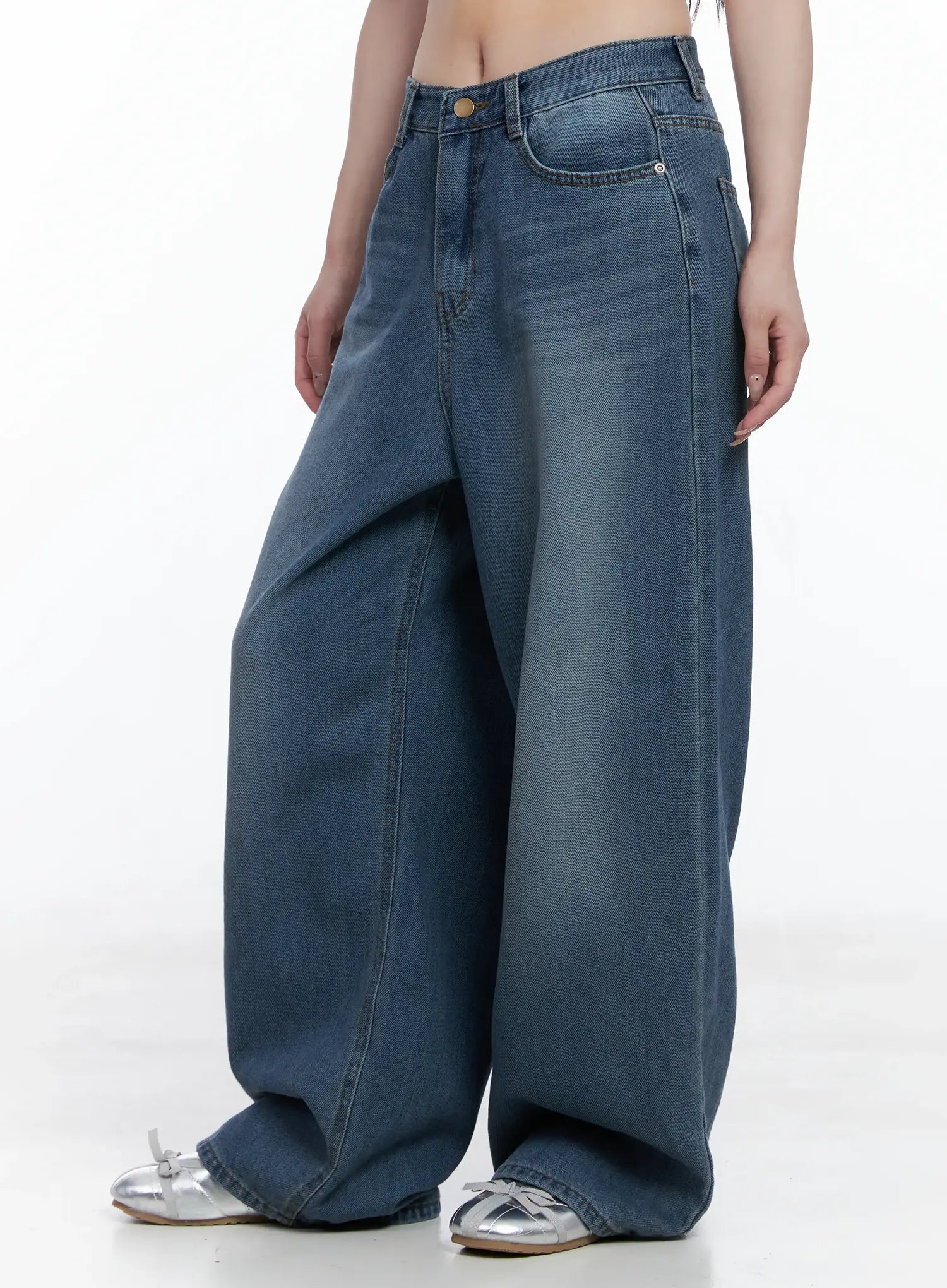 Margot Low-Rise Washed Wide-Leg Jeans CS501 in dark blue, side close-up on model, highlighting dramatic wide-leg sweep and whisker wash detail at hip, with silver bow flats.